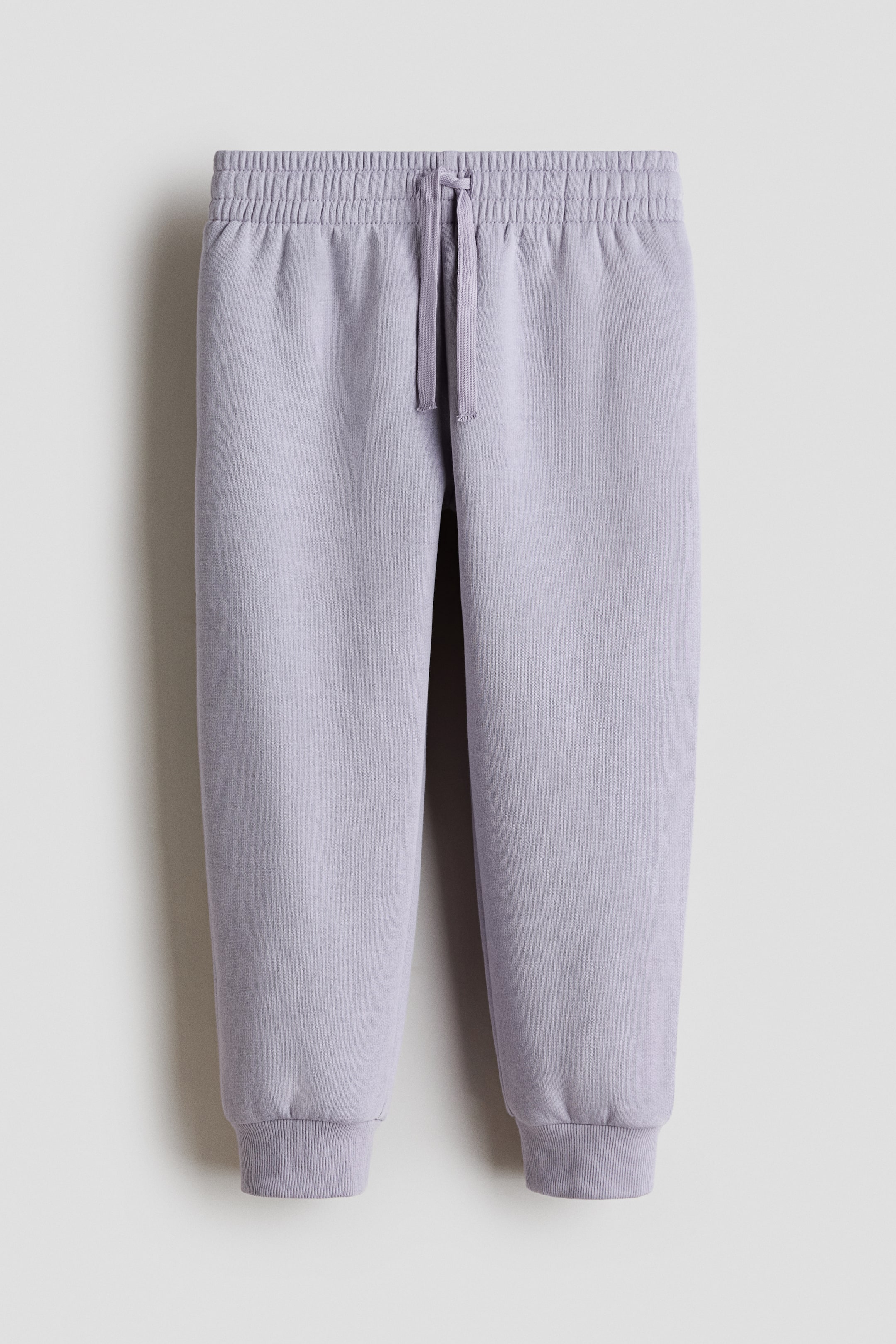 View larger image: Light purple sweatpants are shown from the front, featuring an elastic waistband with a central drawstring tie. The full-length legs taper and finish with ribbed ankle cuffs.