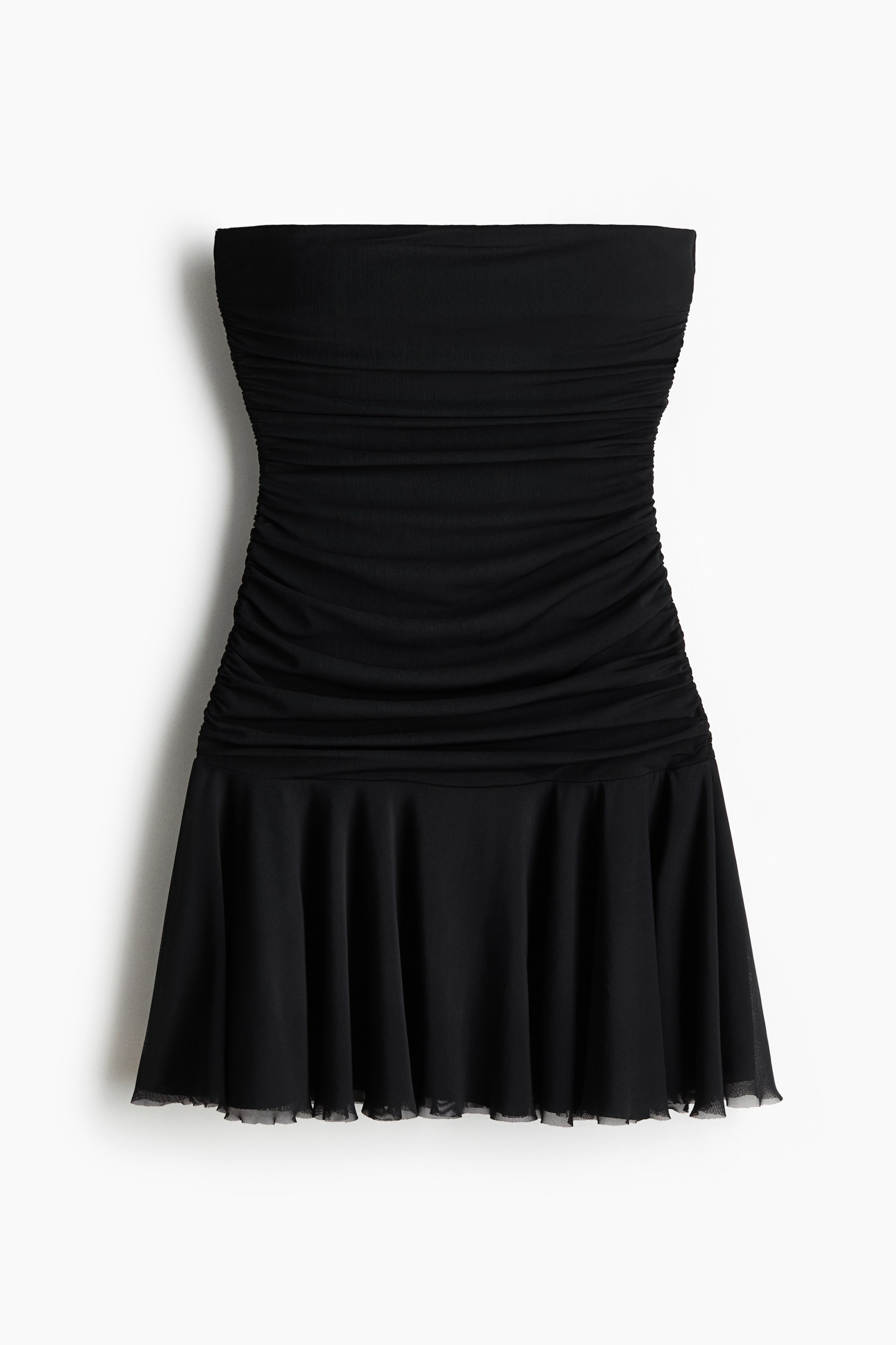 Agrandir l'image: Une robe noire sans bretelles est présentée de face. La robe présente un corsage froncé qui se transforme en une jupe évasée avec une couche noire transparente visible à l'ourlet.
