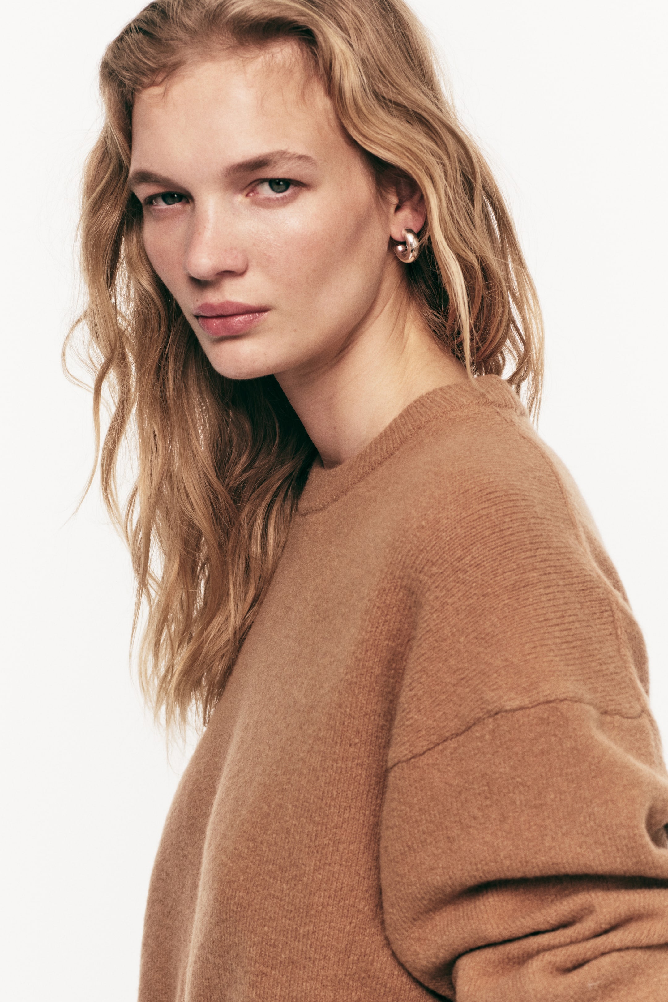 View larger image: An oversized camel-coloured jumper in a soft, brushed knit is worn by the model. It features a round, rib-trimmed neckline and dropped shoulders.
