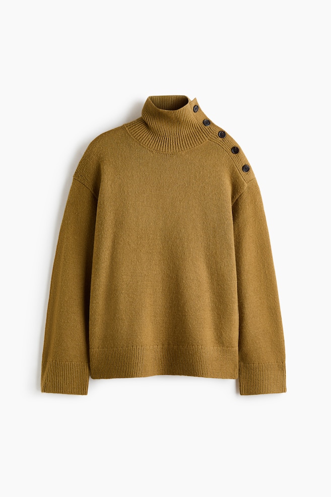 A mustard-brown knit sweater is facing the front, featuring a ribbed high neck with a row of five dark buttons running along the left shoulder seam. The sweater is displaying a relaxed fit with dropped shoulders, long sleeves, ribbed cuffs, and a ribbed hem. - 1