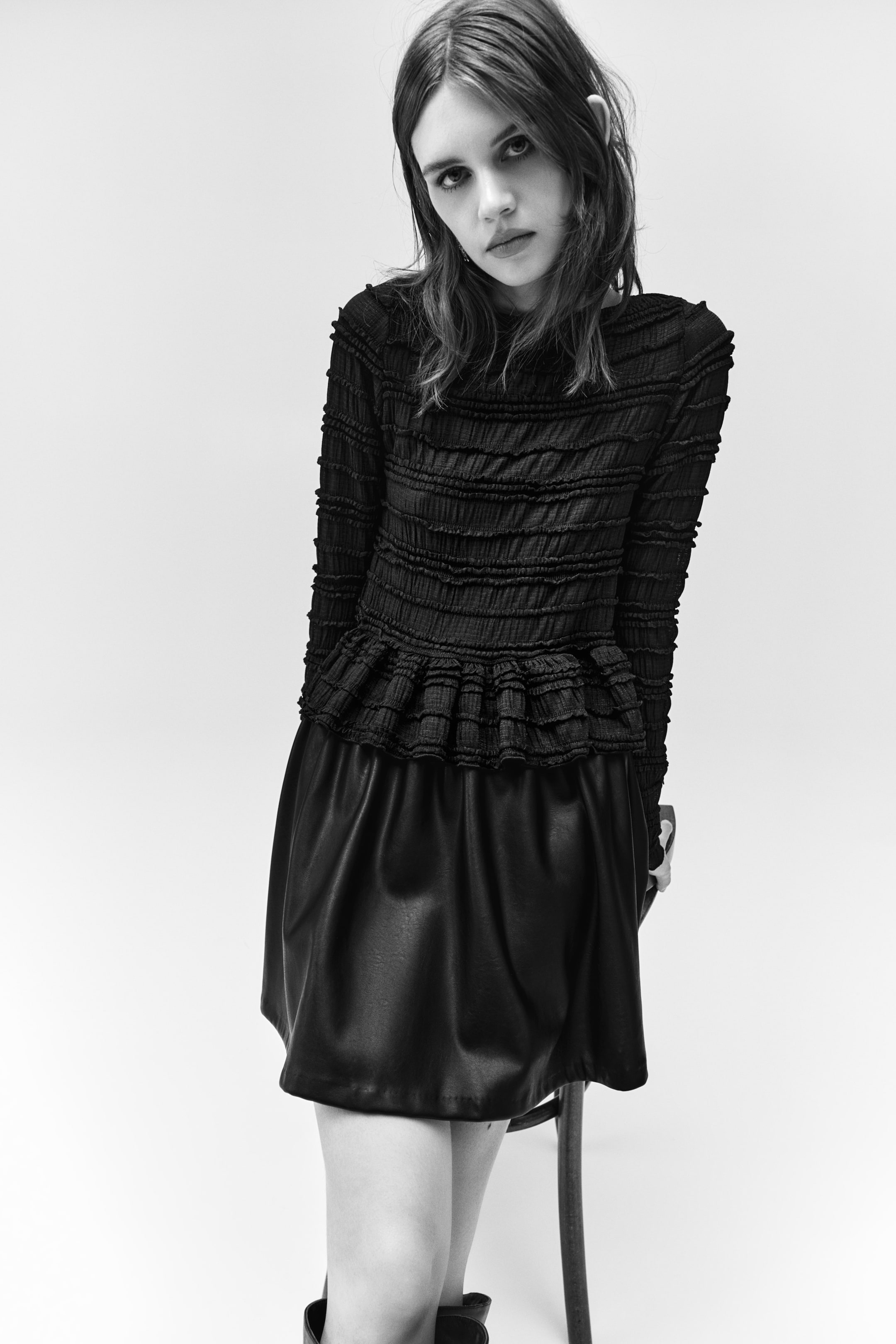 View larger image: The accompanying black mini skirt is showcasing a smooth, slightly shiny faux leather texture and an A-line silhouette.