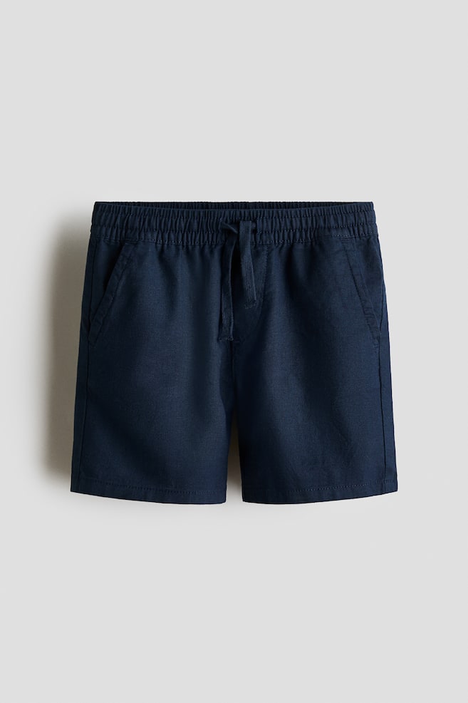 Navy knee-length shorts showcased in a front view, featuring an elasticated drawstring waist and diagonal side pockets. Crafted from a woven linen and cotton blend fabric, these shorts offer both style and comfort. - 1