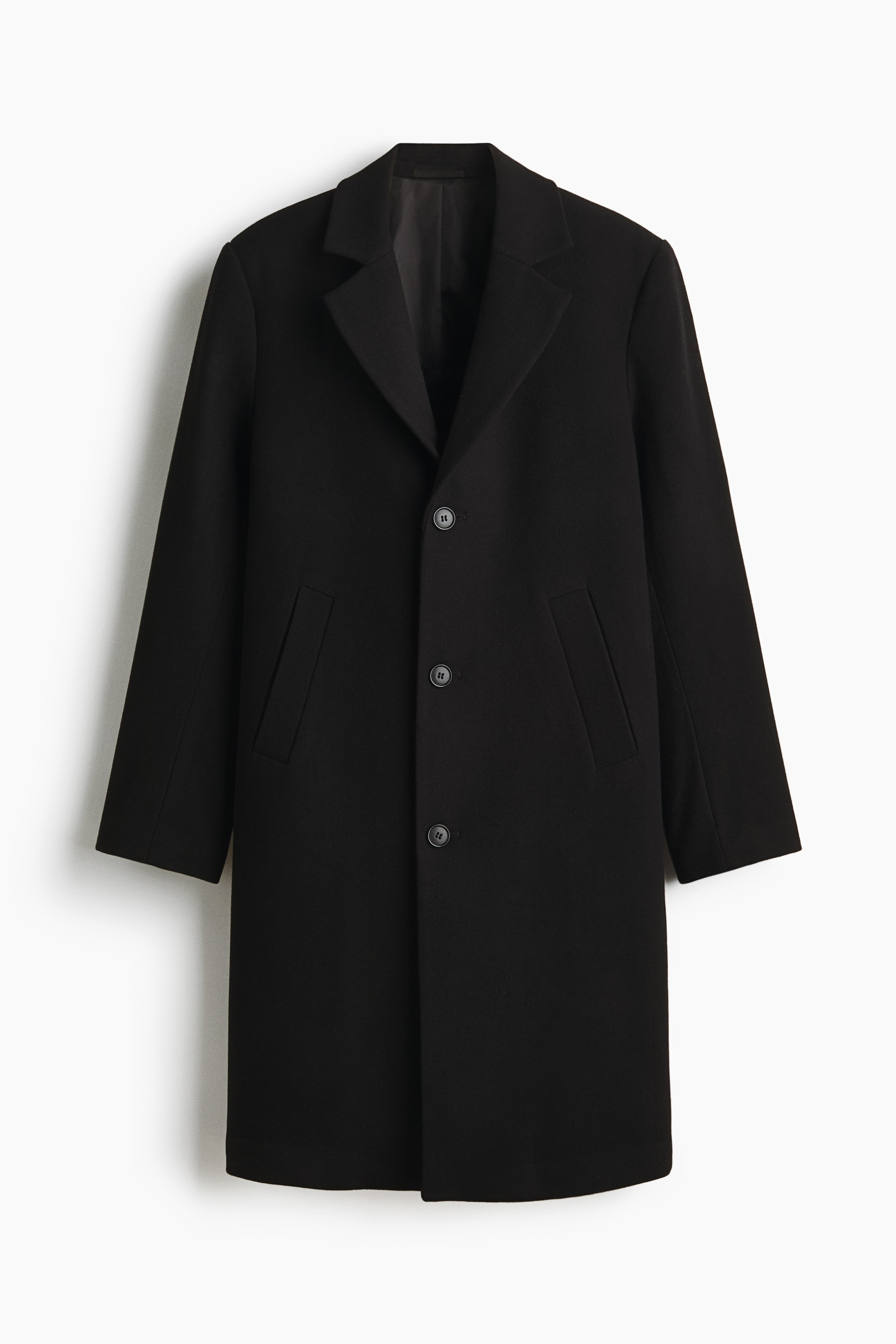 View larger image: A black coat is shown from the FRONT, featuring notch lapels, a three-button front closure with black buttons, and two angled jetted pockets on the front.