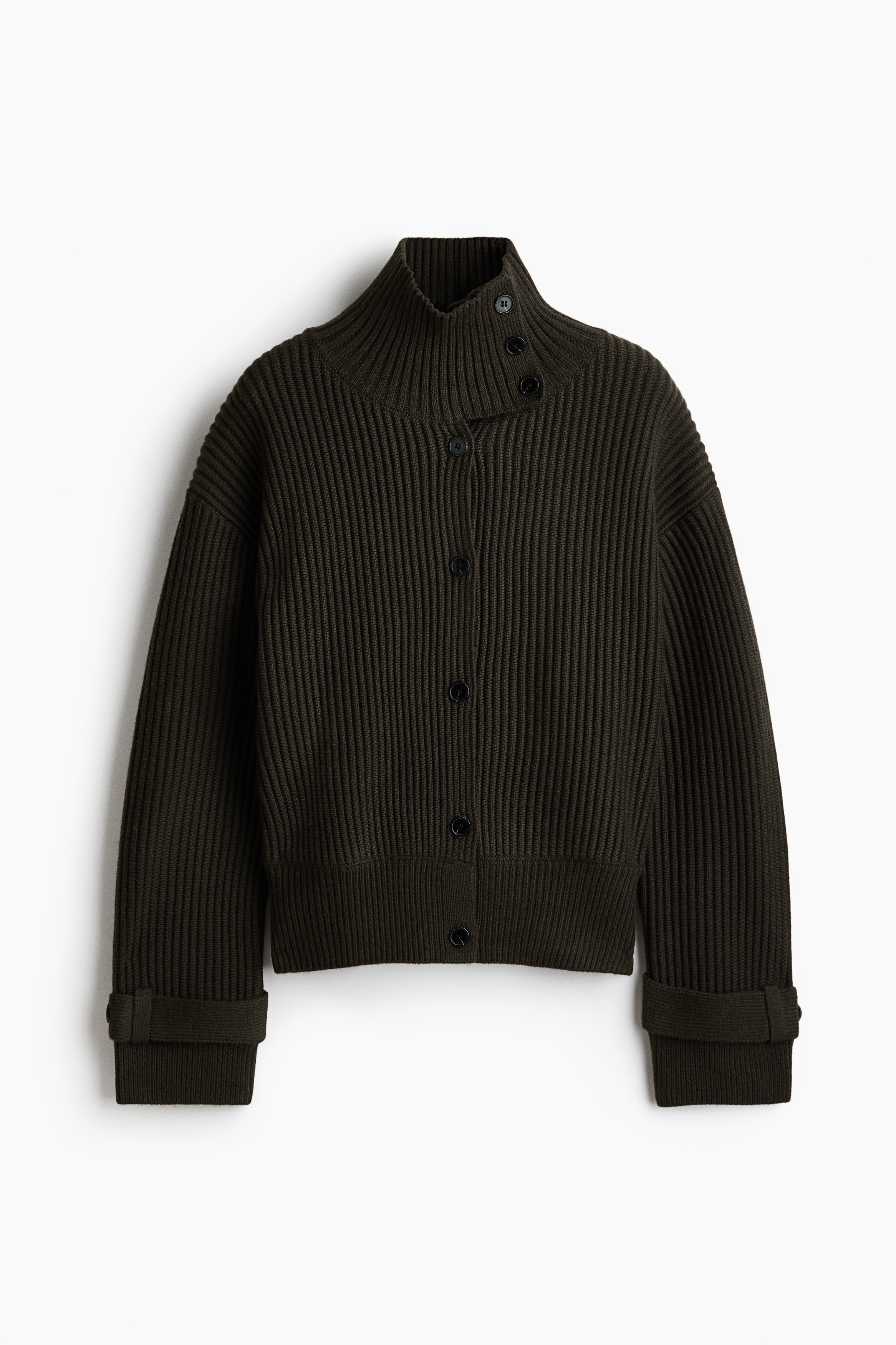 Eine dunkelbraune Strickjacke mit Rippstruktur, einem hohen Kragen mit Knopfleiste, einer vorderen Knopfleiste und Ã¼berschnittenen Schultern wird vom Model getragen. Die Strickjacke ist mit weit geschnittenen weiÃen Hosen und schwarzen Schuhen kombiniert.