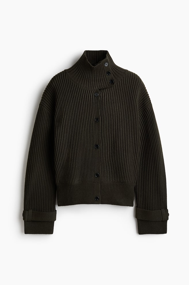 Un cardigan verde mÄsliniu Ã®nchis, cu texturÄ ribatÄ, este prezentat din faÈÄ, avÃ¢nd guler Ã®nalt cu o clapetÄ cu nasture pe o parte Èi Ã®nchidere cu nasturi. Designul include umeri cÄzuÈi, mÃ¢neci lungi cu detalii cu clapetÄ Èi nasture la manÈetele ribate Èi tiv ribat. - 1