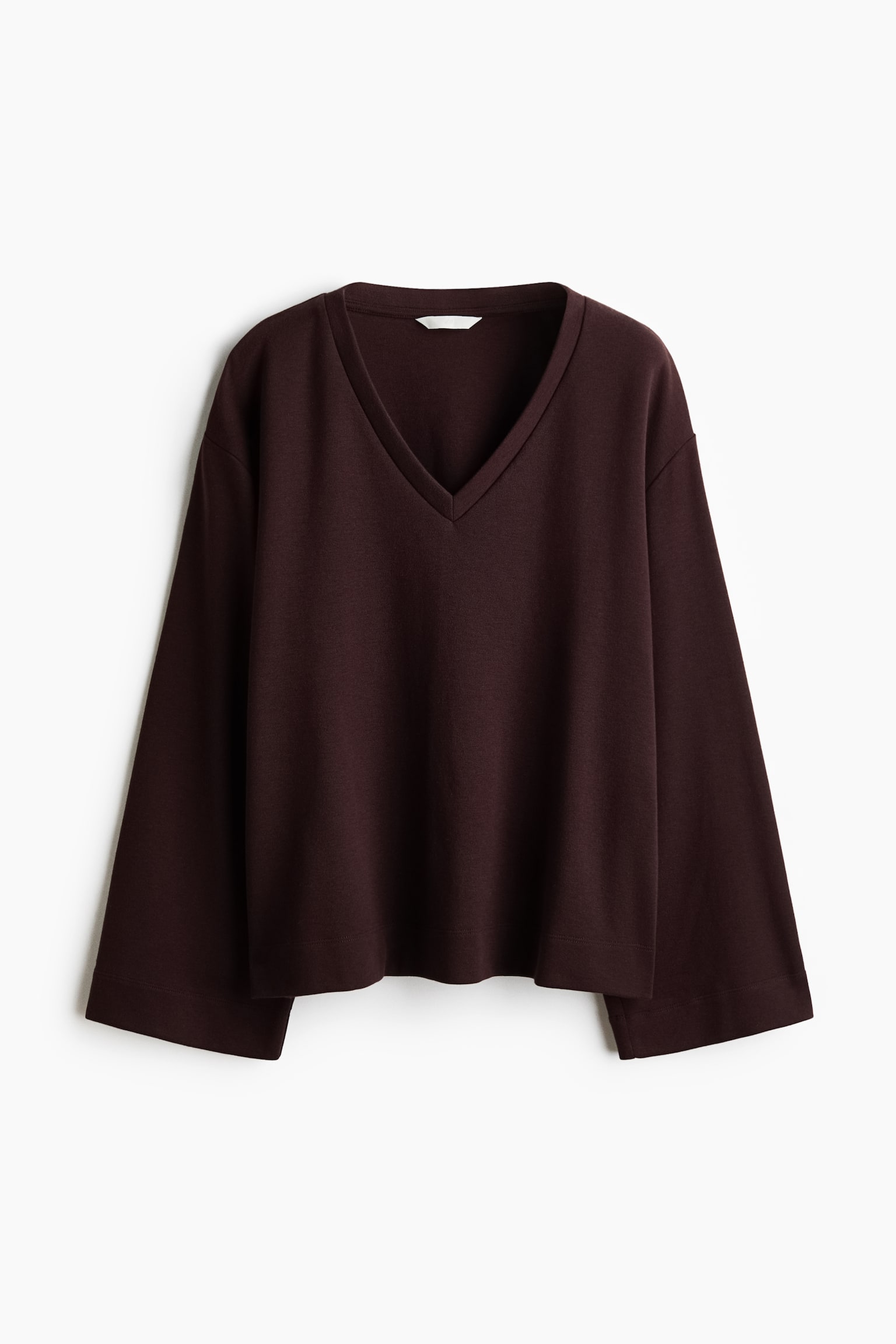 A dark brown V-neck top is hanging in a front-facing view, featuring a loose, boxy silhouette with dropped shoulders and wide, long sleeves. The top is designed with a banded V-neckline and a straight hem.