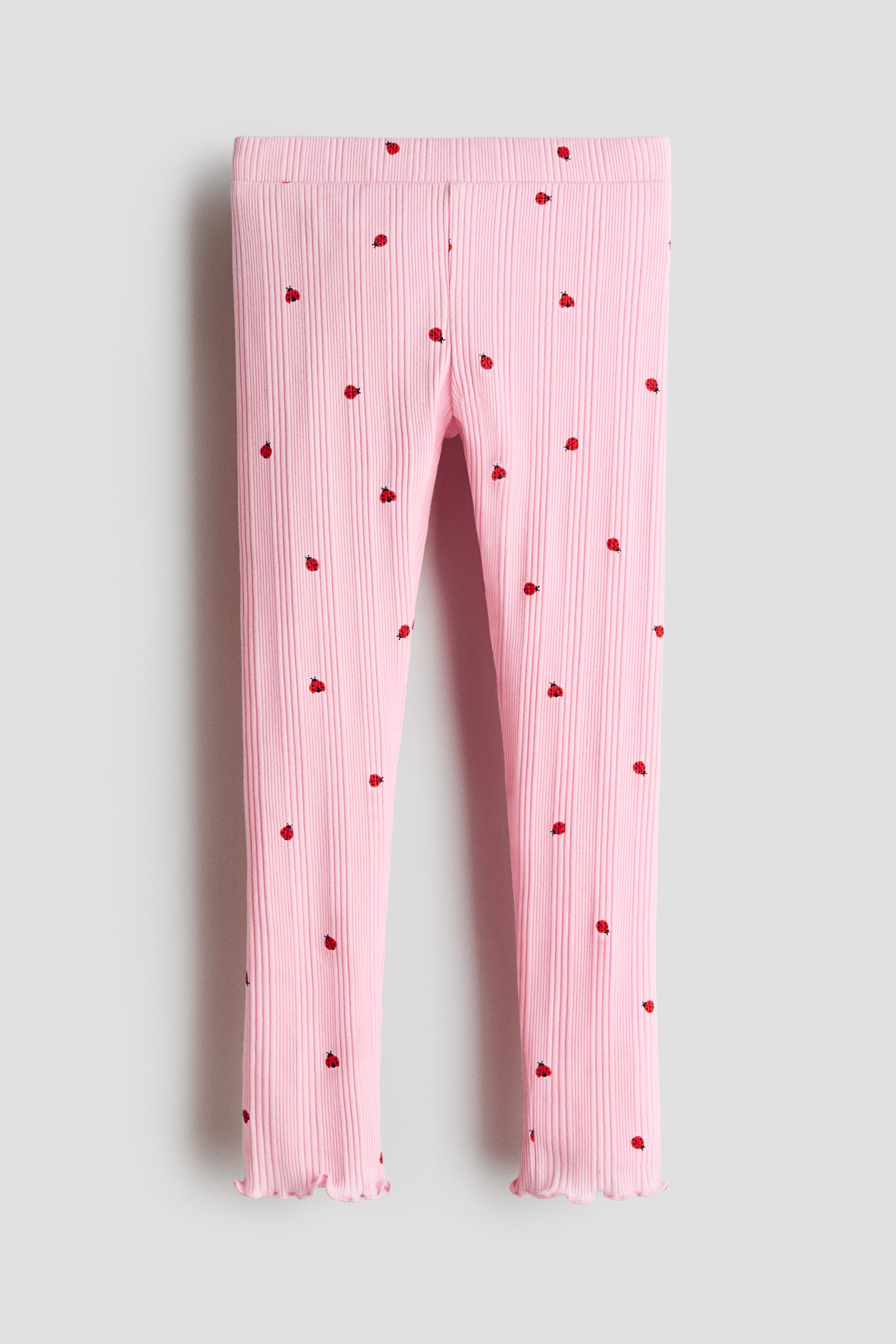 Büyük resmi görüntüle: Pembe nervürlü pamuklu jarse taytlar, önden görünen, tamamı uğur böceği baskılı. Bunlar belde kapalı lastikleme ve paçalarda overlok dikişleri ile tasarlanmış olup, fırfırlı bir görünüm yaratmaktadır.