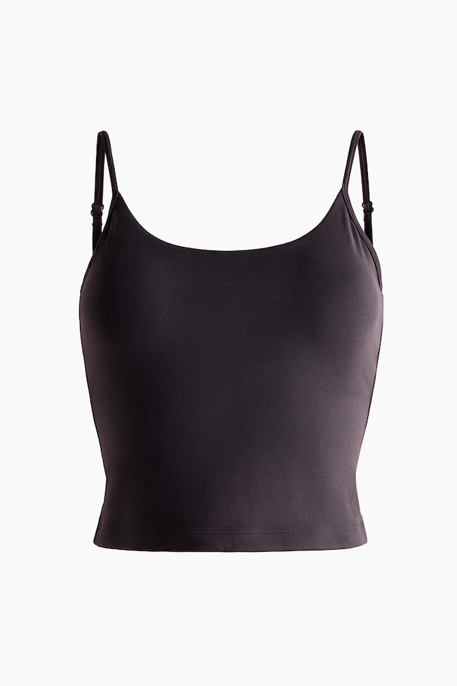 Ein dunkelbraunes Crop-Top mit SpaghettitrÃ¤gern ist von vorne zu sehen und verfÃ¼gt Ã¼ber dÃ¼nne, verstellbare TrÃ¤ger sowie einen runden Ausschnitt. Das eng anliegende KleidungsstÃ¼ck zeigt eine glatte Textur mit sauber verarbeitetem, verkÃ¼rztem Saum. - 1
