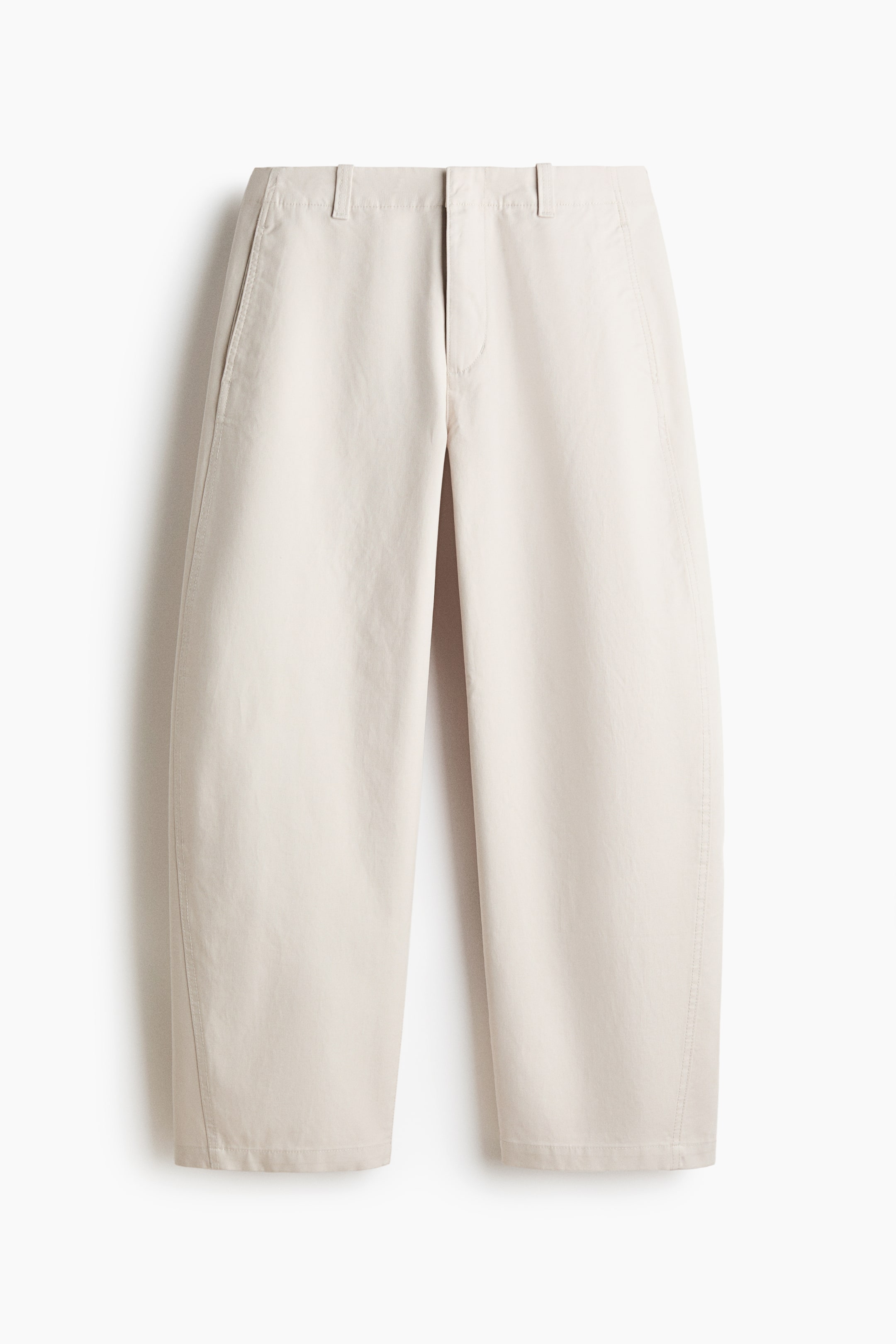 View larger image: The light beige trousers are facing forward, featuring a flat front waistband with belt loops and side slash pockets. They showcase a wide, slightly barrel-shaped leg silhouette with vertical stitched seams running down the front of each leg to a cropped hem.