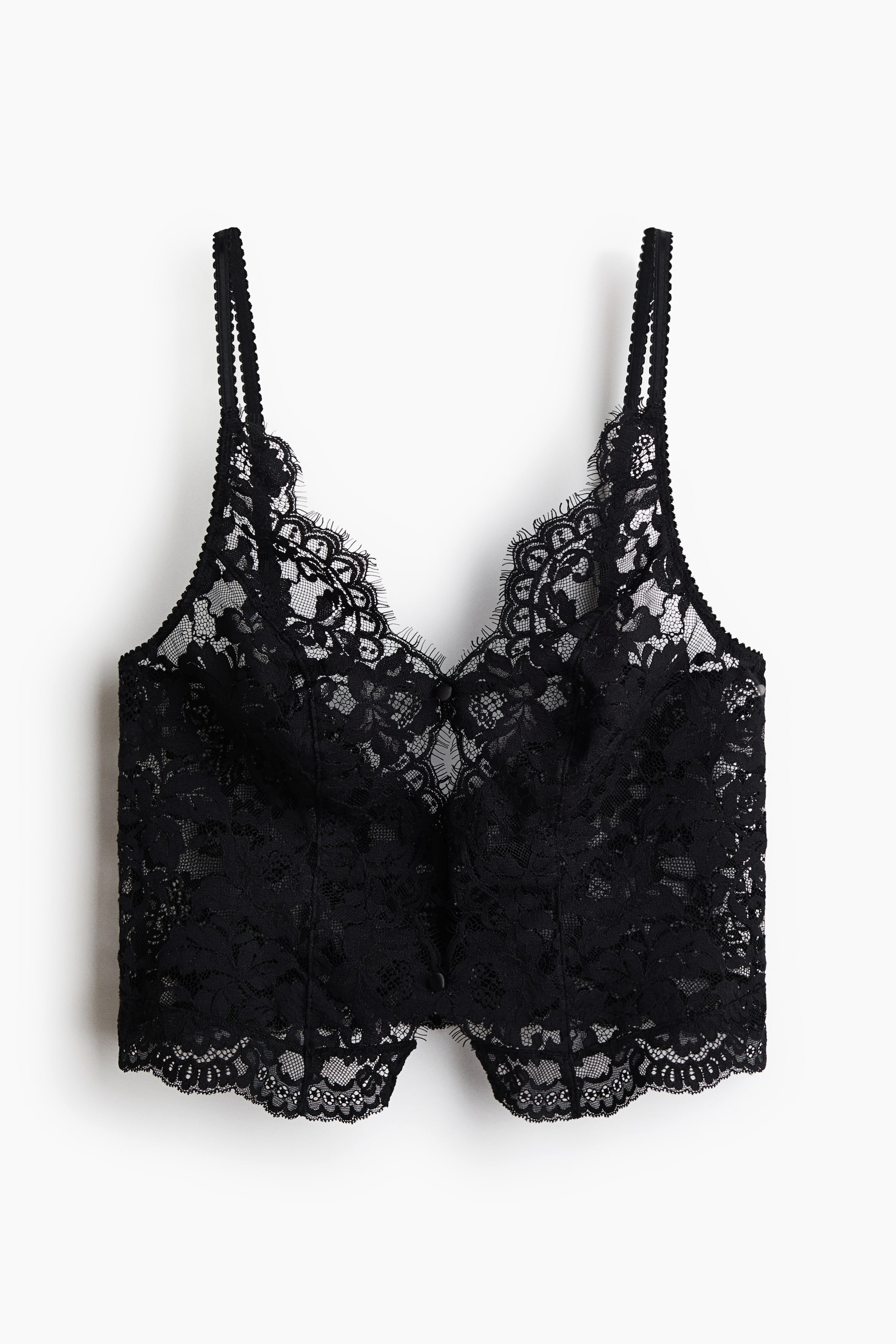 Se større billede: En sort blondebralette vises forfra med en buet V-udskæring med bølgekant og tynde dobbelte spaghettistropper. Den fremhæver et gennemsigtigt blomsterblondemønster over hele modellen samt små knapdetaljer midt foran og en let buet blondekant forneden.