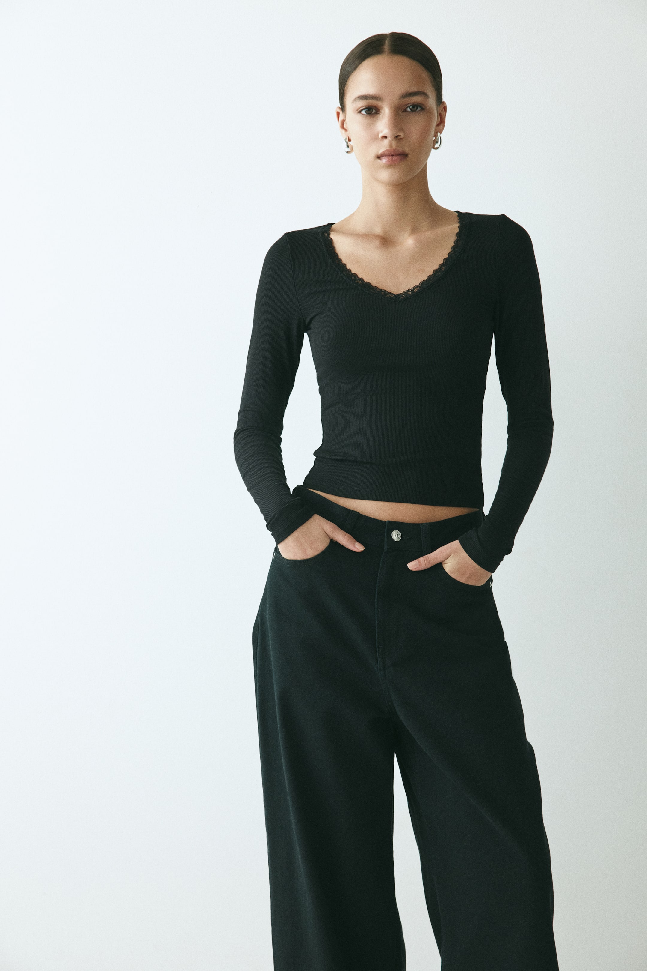 View larger image: A black long-sleeve ribbed top featuring a fitted silhouette and a V-neckline with lace trim.