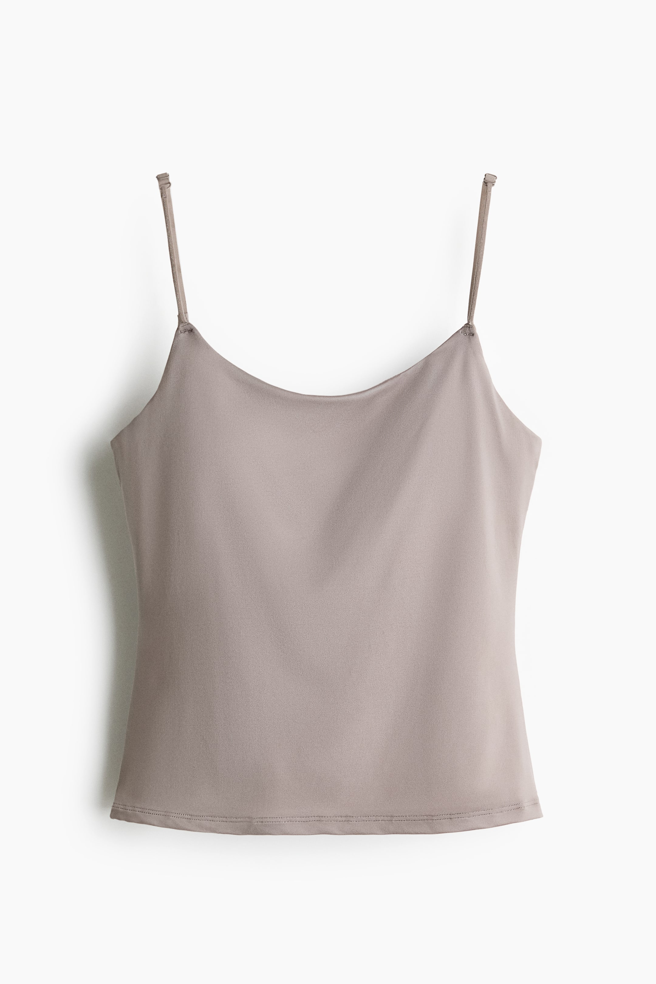 이미지 확대 보기: 은은한 베이지 컬러의 캐미솔 톱이 매끄러운 원단, 섬세한 스파게티 스트랩, 부드럽게 굴곡진 네크라인을 드러내고 있습니다.