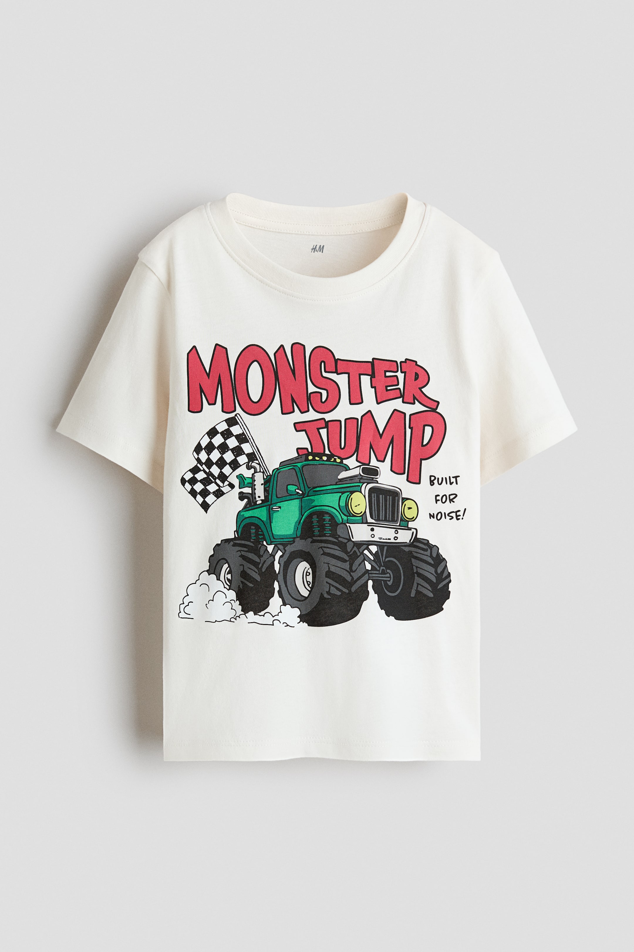 View larger image: A printed cotton jersey T-shirt is shown from the front, featuring a round ribbed neckline and gently dropped shoulders. The print depicts red text reading "MONSTER JUMP" above a green monster truck with a checkered flag and the text "BUILT FOR NOISE!".