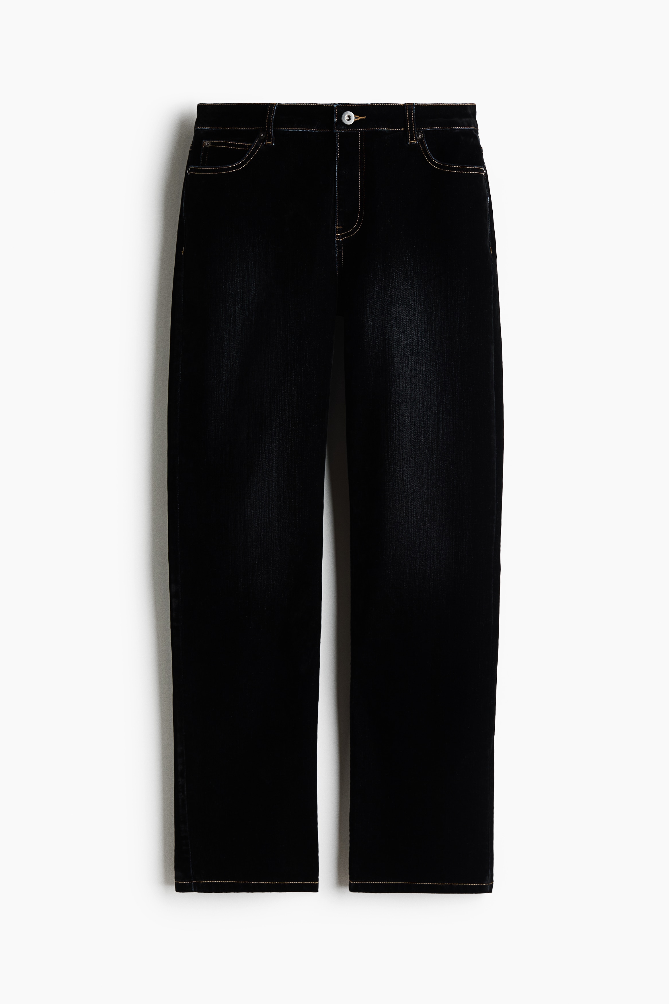 Jean en denim noir Ã  jambe droite et coupe rÃ©guliÃ¨re, portÃ© par le mannequin qui sâappuie contre une chaise en mÃ©tal. Le jean est assorti Ã  un haut blanc sans manches Ã  volants et Ã  des sandales noires Ã  talons.