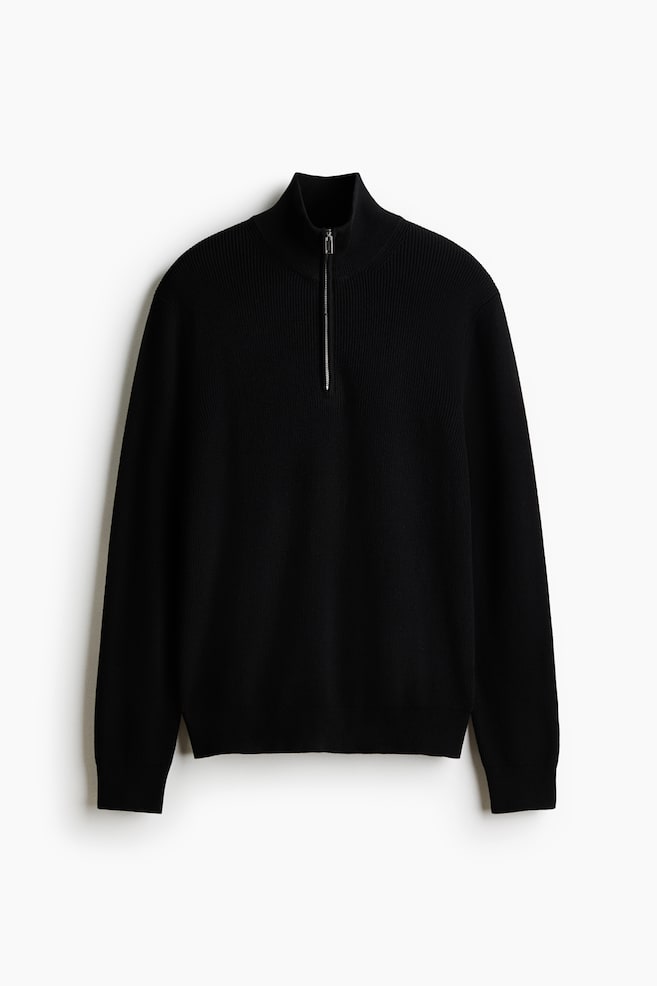 A black quarter-zip jumper is showcasing a ribbed knit texture and a high collar with a silver-toned zip. It features long sleeves with ribbed cuffs and a ribbed hem, presented from the front. - 1