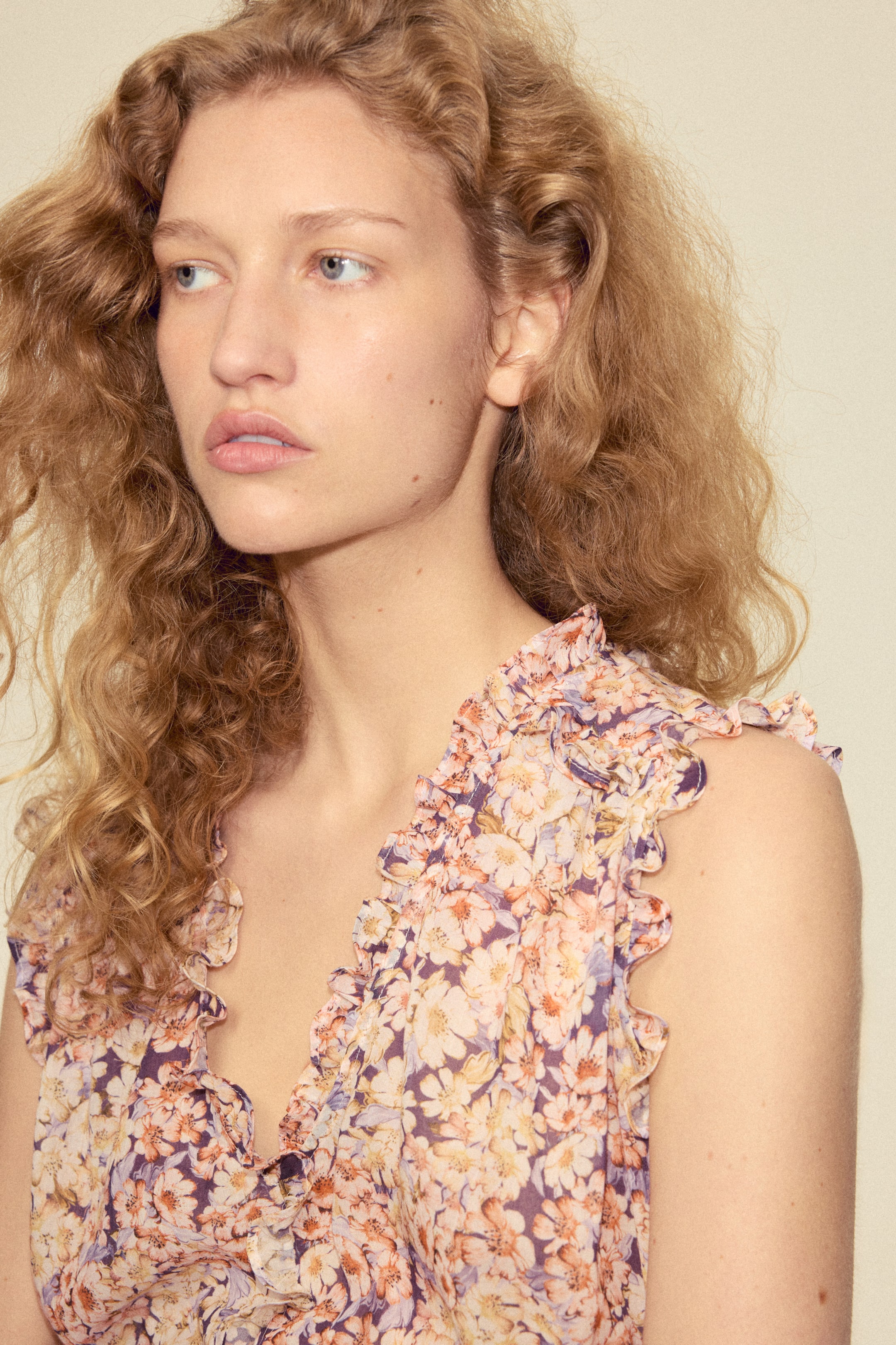 View larger image: The model is wearing a short, sleeveless top crafted from a breezy floral weave. The top is adorned with frill trims along its deep V-neckline and armholes.