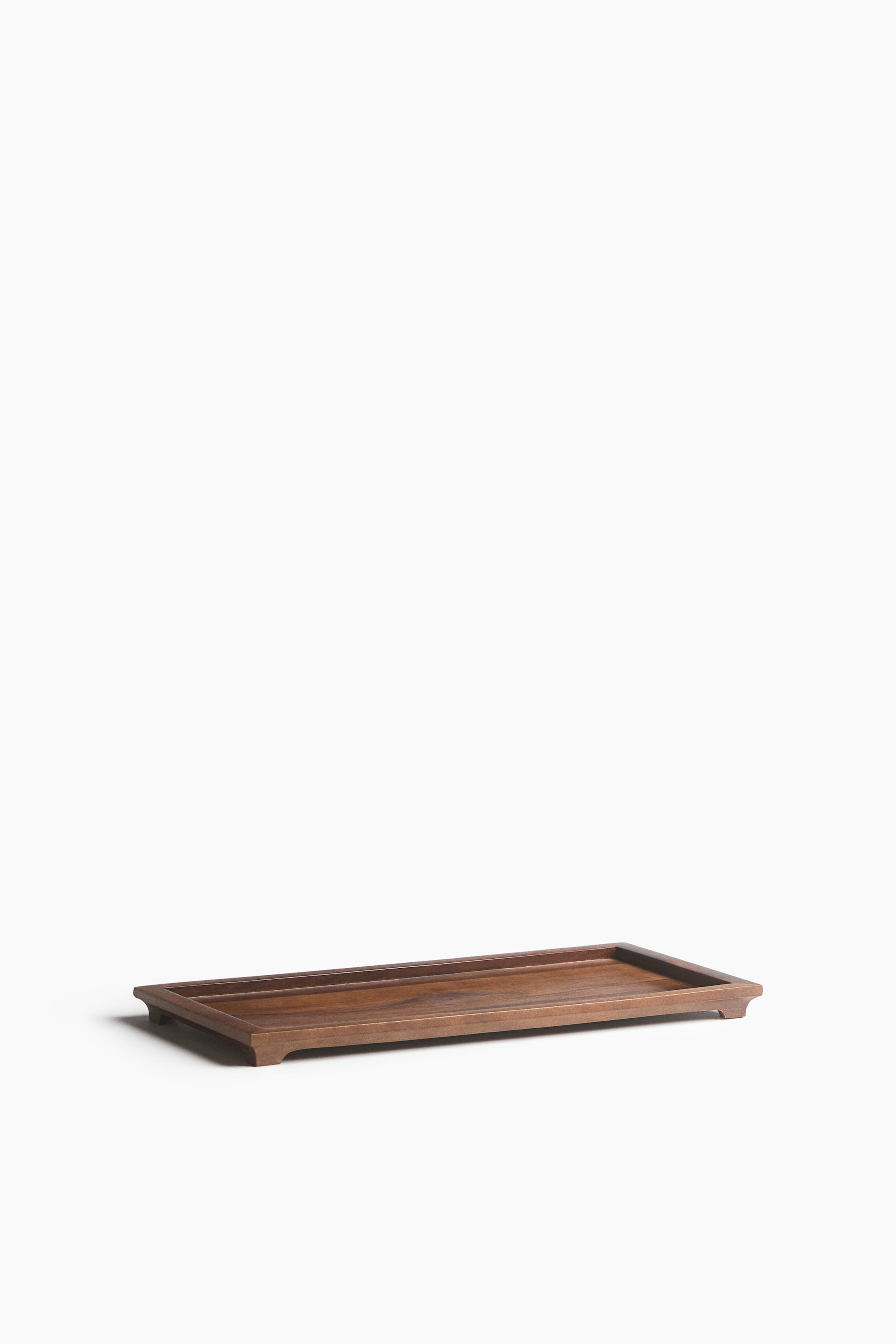 View larger image: A rectangular dark wood tray is positioned at a three-quarter angle, featuring a raised outer rim and small corner feet that elevate the base. The tray has a smooth finish with visible natural wood grain.