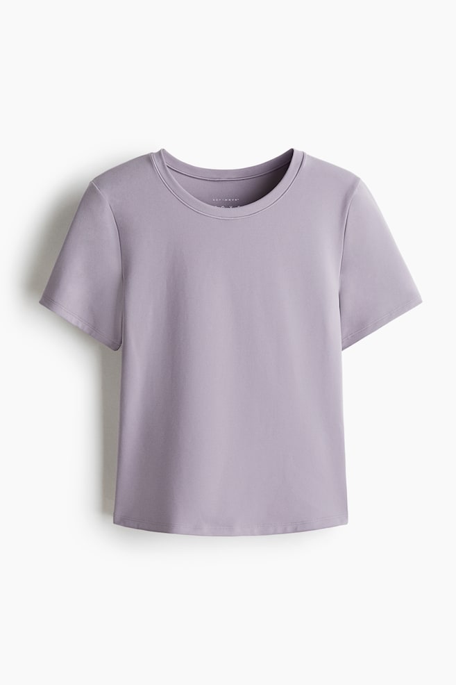 A light purple sports t-shirt is being presented from the front, featuring a round neck, short sleeves, and a slightly curved hem, with its neck tag displaying "SOFT MOVE". - 1