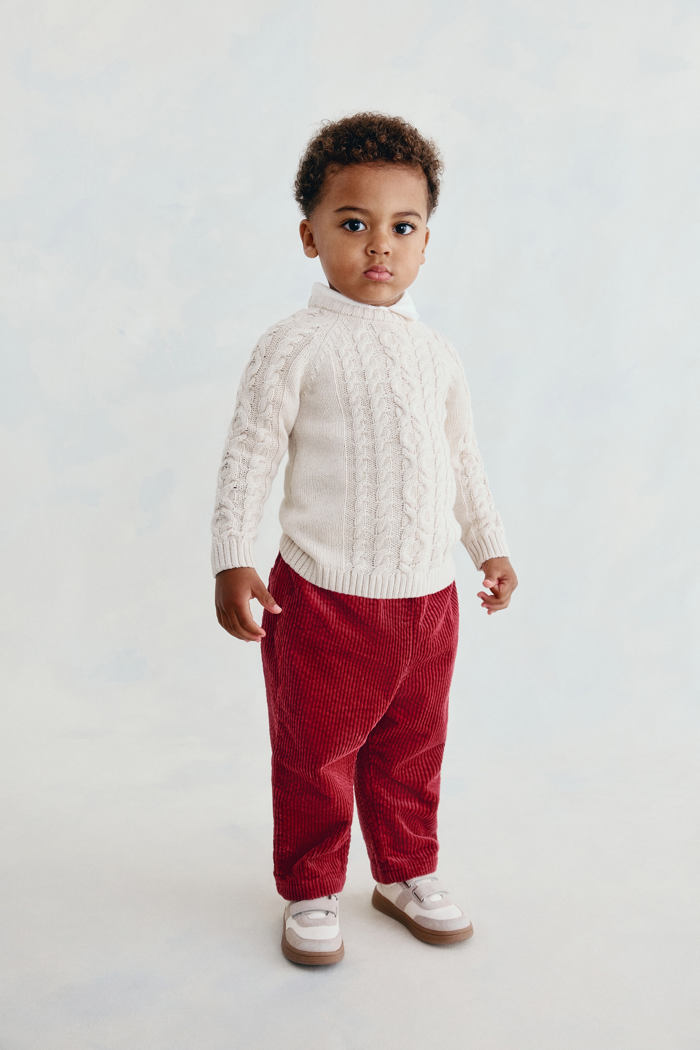 Une paire de pantalons en velours cÃ´telÃ© rouge foncÃ© est posÃ©e Ã  plat, vue de face, mettant en valeur une taille Ã©lastiquÃ©e froncÃ©e, des poches latÃ©rales et une coupe droite. Le tissu texturÃ© Ã  cÃ´tes court verticalement sur toute la longueur des jambes jusquâaux ourlets droits.