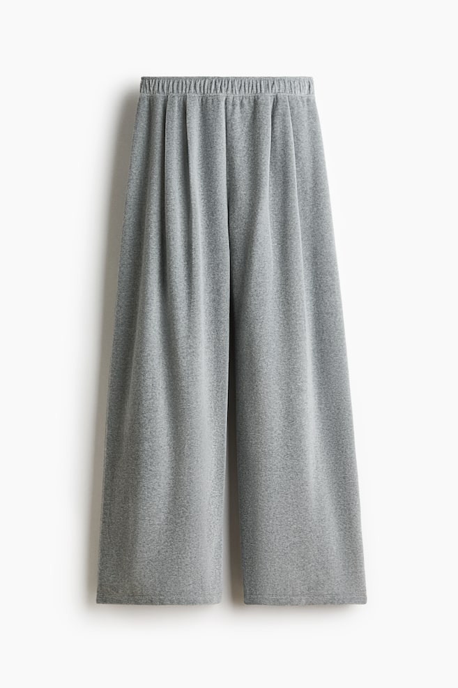 Grey wide-leg pants are displaying a loose, relaxed fit from the front. They are featuring an elasticized, gathered waistband at the top, and the heather grey marled fabric is finishing with a plain hem. - 1