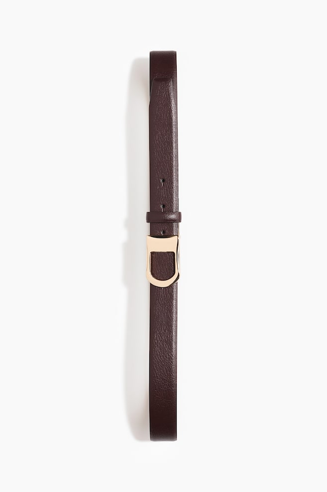 A dark brown leather belt lies flat and vertically oriented, showcasing a fine-grained texture. It features a polished gold-toned stirrup-shaped buckle, a matching leather strap keeper, and several adjustment holes along the strap. - 1