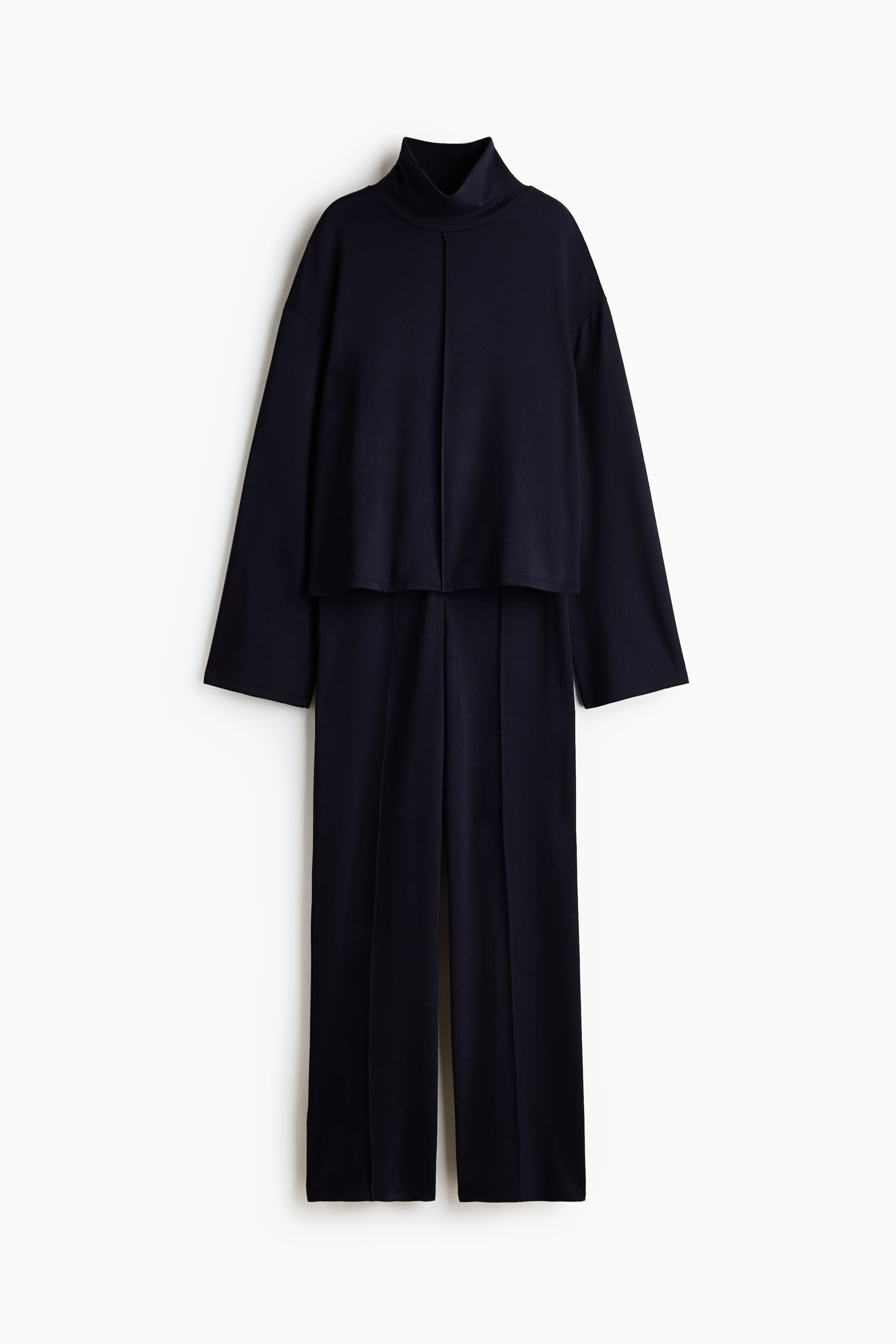 查看大圖: 深藍色厚重針織套裝從正面展示,特色是雙層高領上衣,前面有外露縫線,落肩設計,長袖。配套的褲子設計為直筒褲,前面有縫製的摺痕。