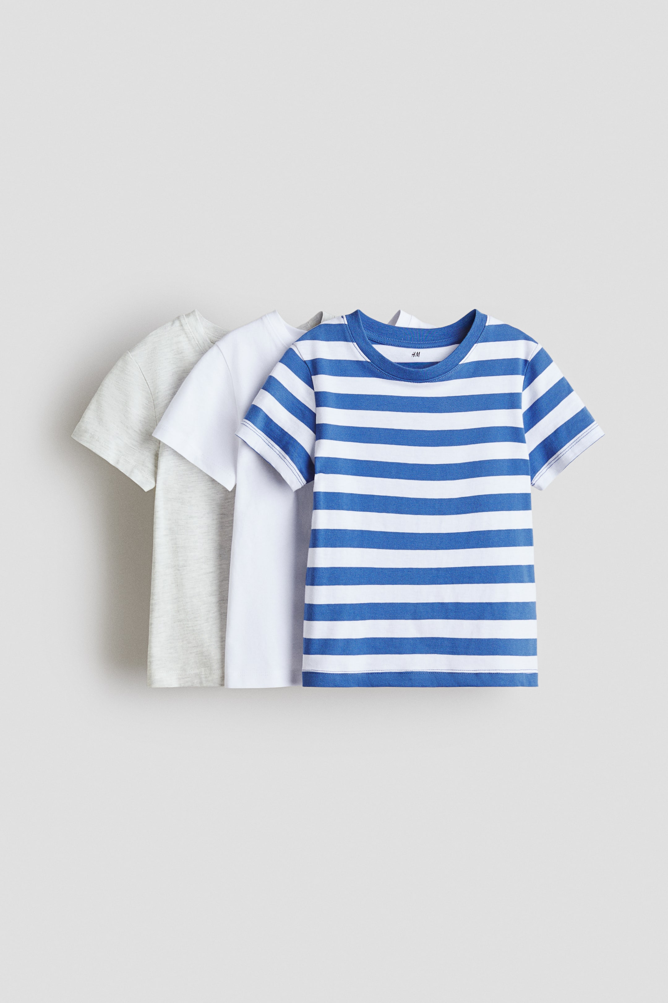 View larger image: Displayed are three short-sleeved T-shirts crafted from soft cotton jersey, viewed from the front. The T-shirt in the forefront showcases blue and white stripes, while a plain white T-shirt and a light grey marl T-shirt are positioned behind it. All feature a round, rib-trimmed neckline.