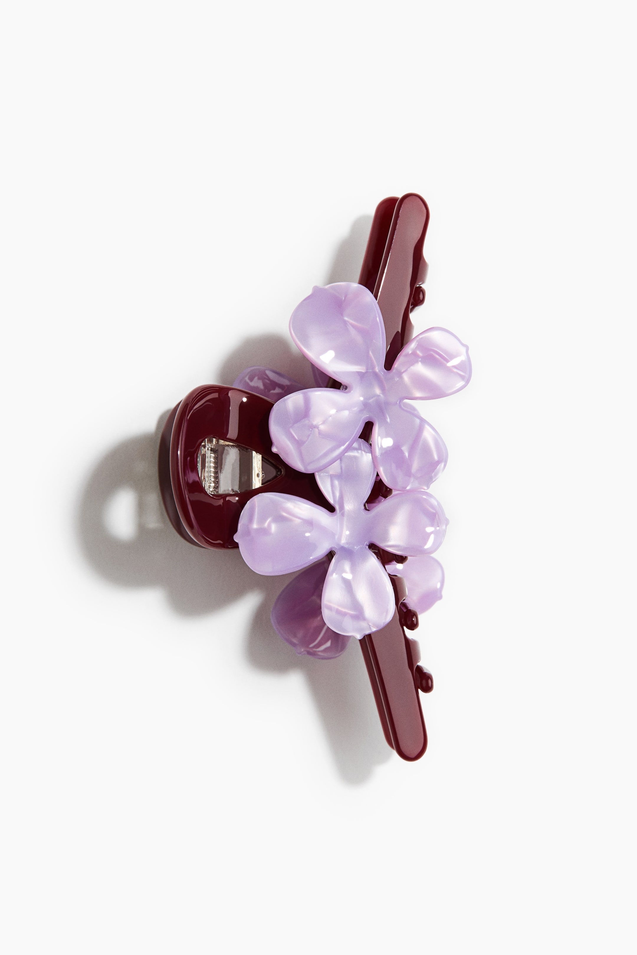 View larger image: The hair claw clip showcases a glossy, deep red base. It is adorned with three prominent, light purple, pearlescent flower shapes on the top, presented at a slight angle.