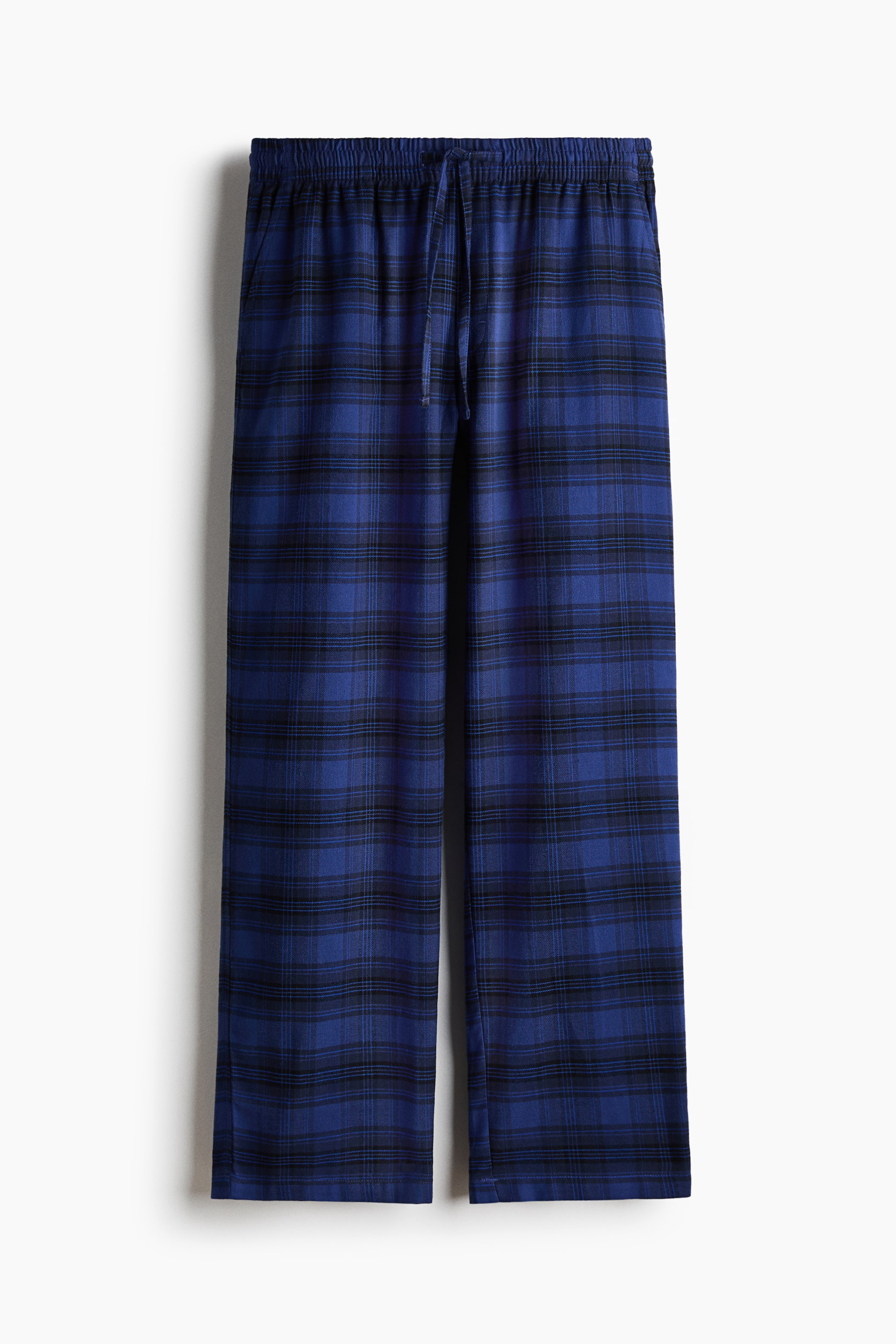 View larger image: Trousers feature a blue and black plaid pattern on soft cotton flannel fabric, shown in a front view. They are designed with an elasticated drawstring waist and diagonal side pockets, offering a relaxed fit.
