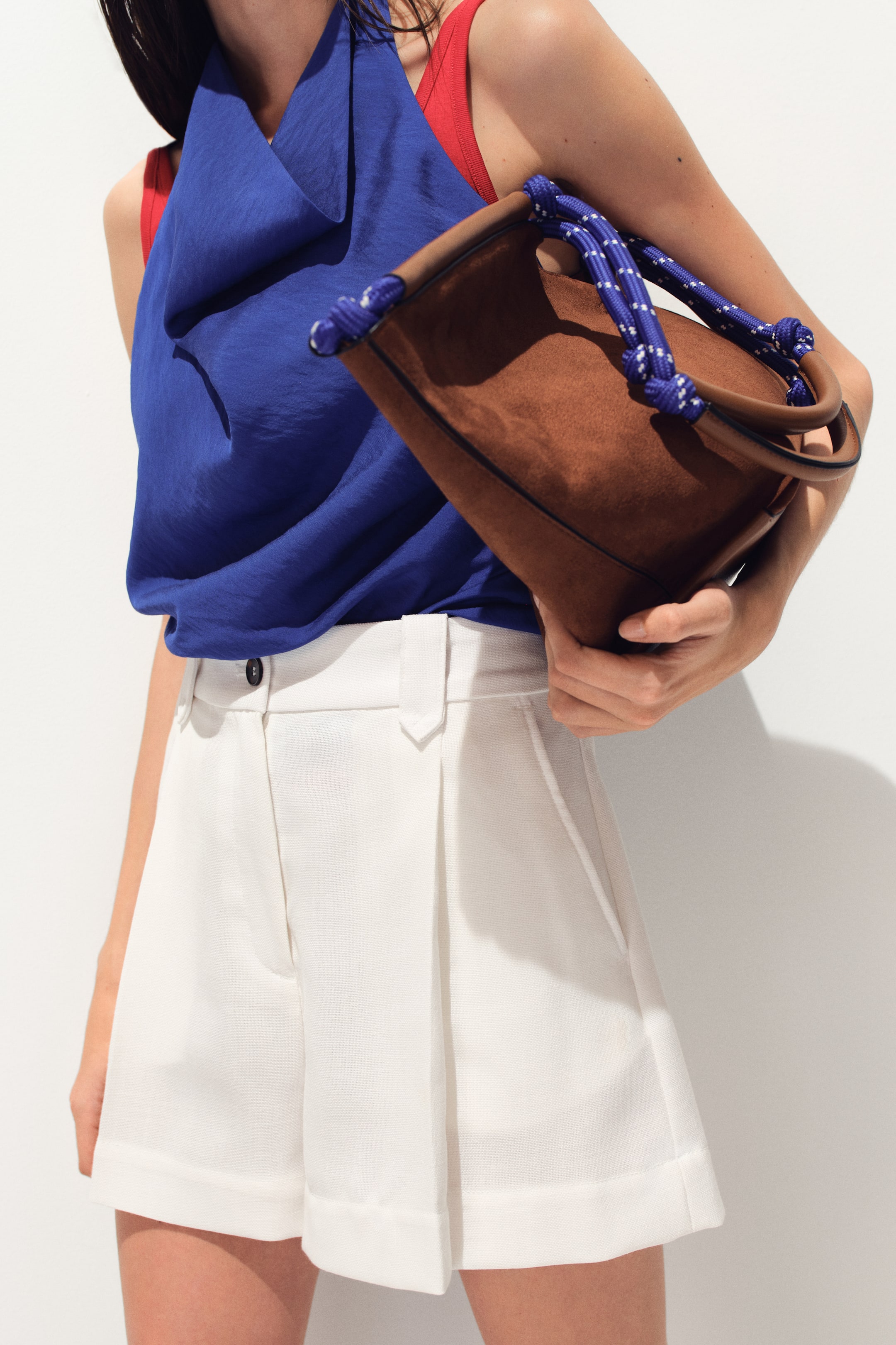 View larger image: The white shorts showcase a pleated front, cuffed hem, and a waistband with a visible button closure and belt loops. They are slightly angled to the right, highlighting the side pockets and the textured fabric.