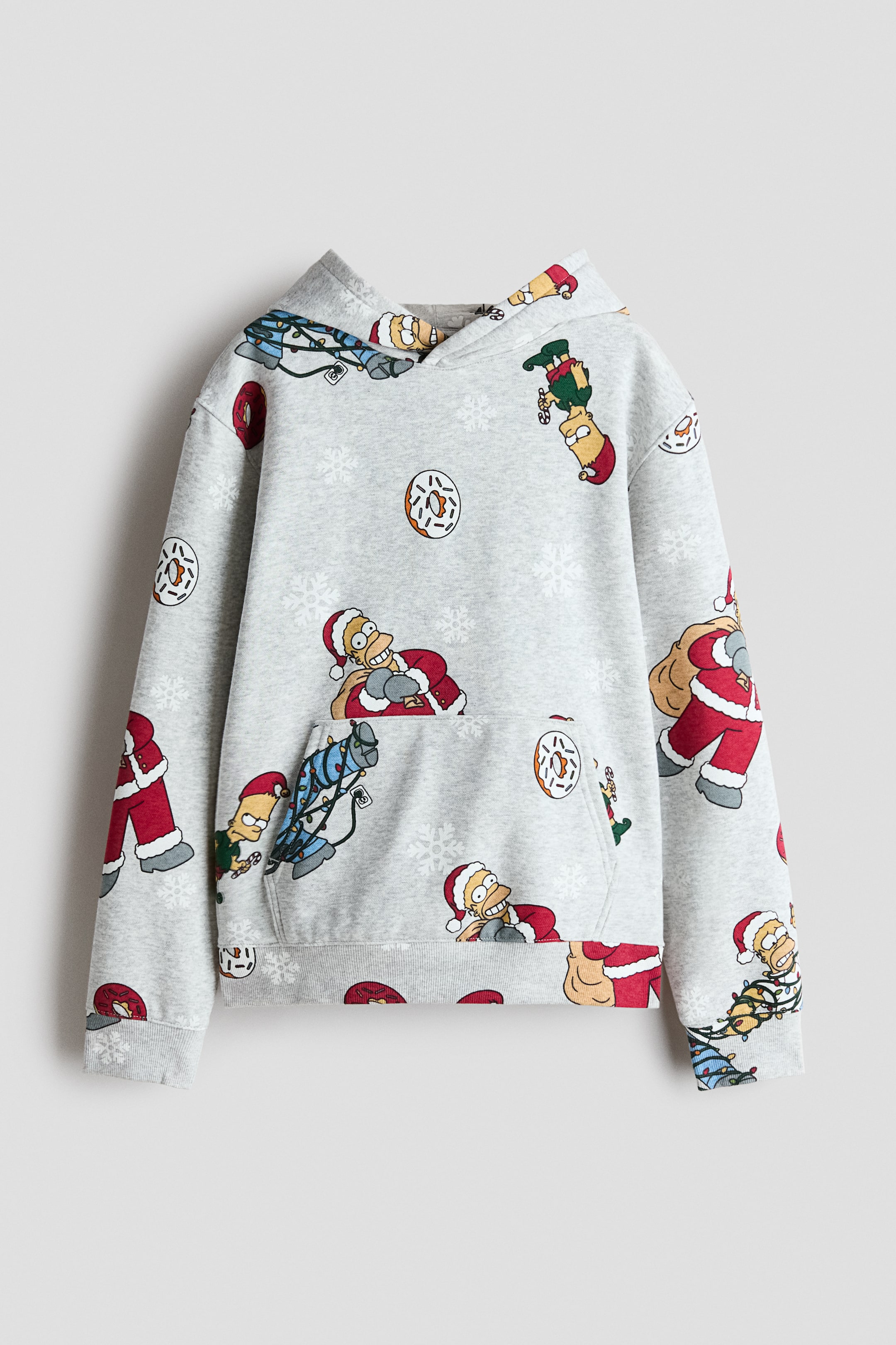 View larger image: A light gray fleece hoodie is shown from the front, featuring a wrap hood, dropped shoulders, a kangaroo pocket, and ribbed trim at the cuffs and hem. It displays an all-over printed holiday pattern with cartoon characters, snowflakes, and frosted donuts.
