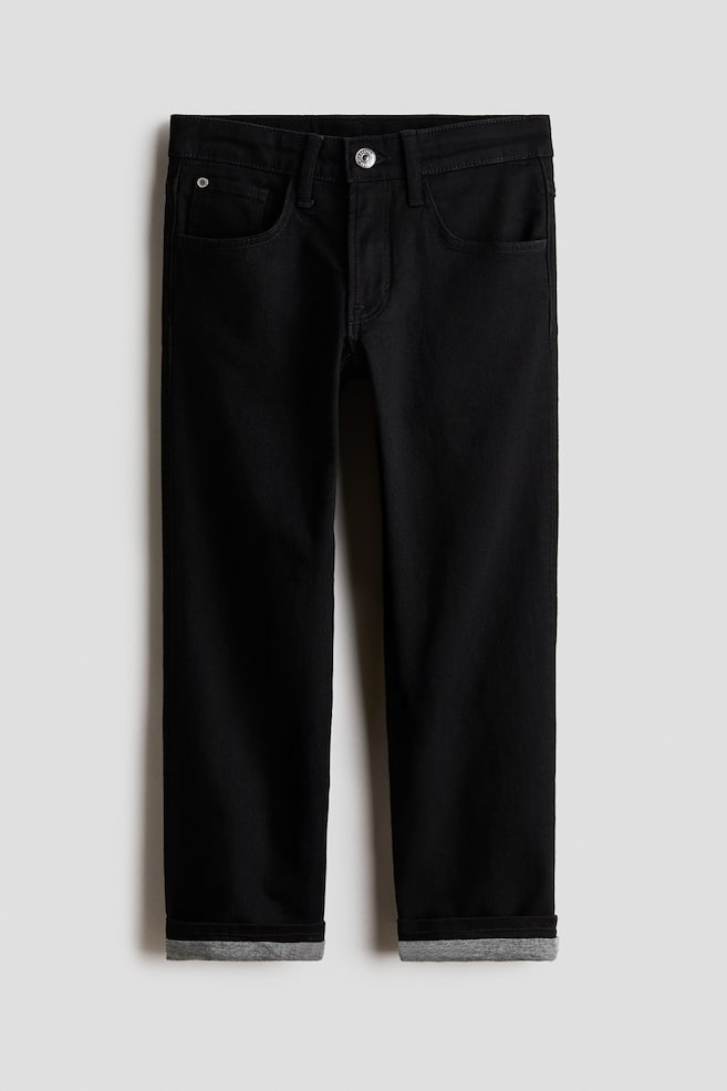 A pair of black straight-leg jeans is shown from the front, featuring a five-pocket design, belt loops, and a silver button fastening. The hems are turned up, revealing a contrasting grey lining. - 1