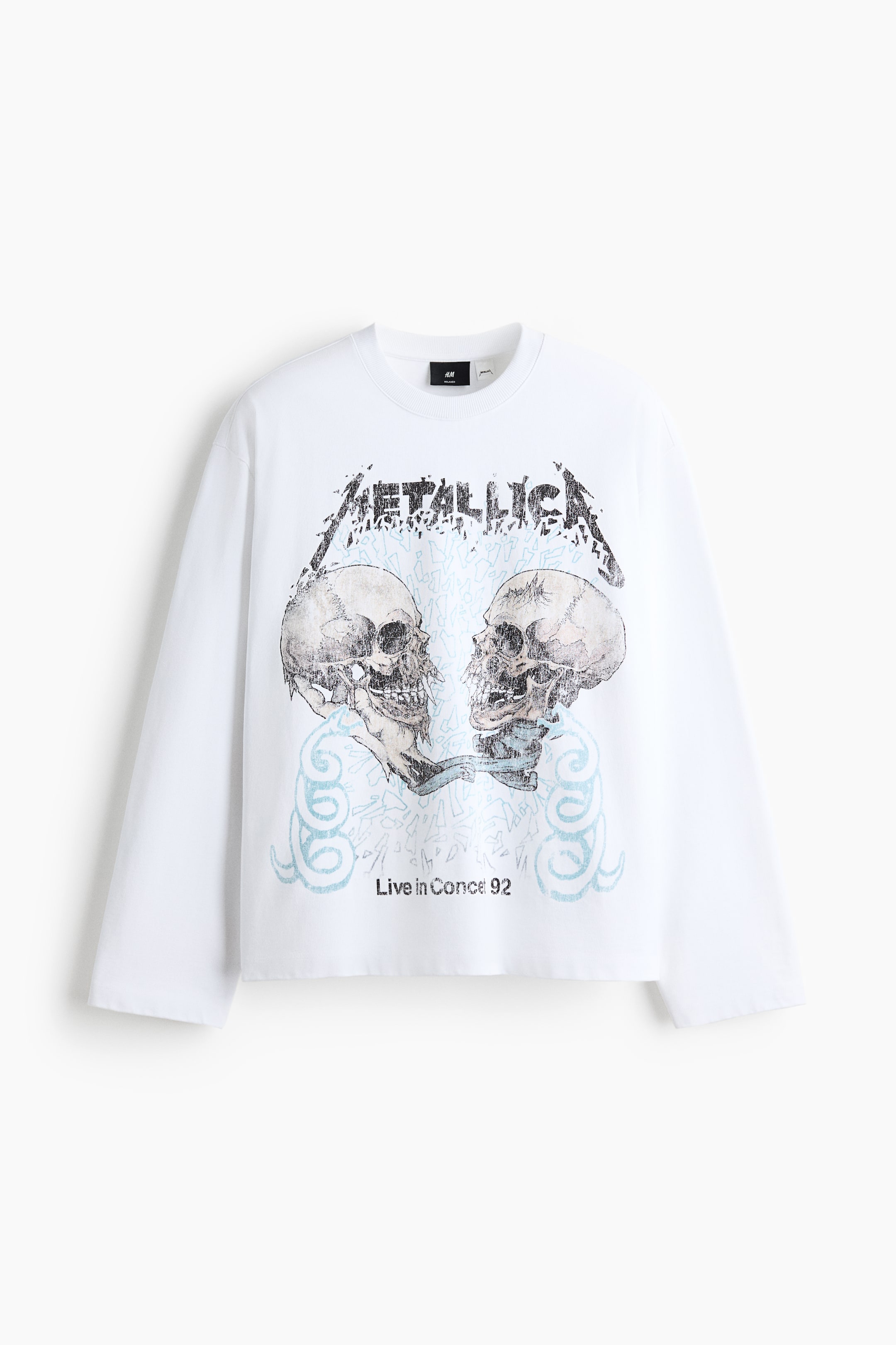 Ver imagen más grande: Sudadera blanca de manga larga y cuello redondo con un ajuste holgado. El frente de la sudadera muestra un logo "METALLICA" desgastado sobre dos calaveras humanas detalladas enfrentadas, rodeadas de patrones ondulados y dentados en azul claro, y el texto "Live in Conce 92" posicionado debajo.