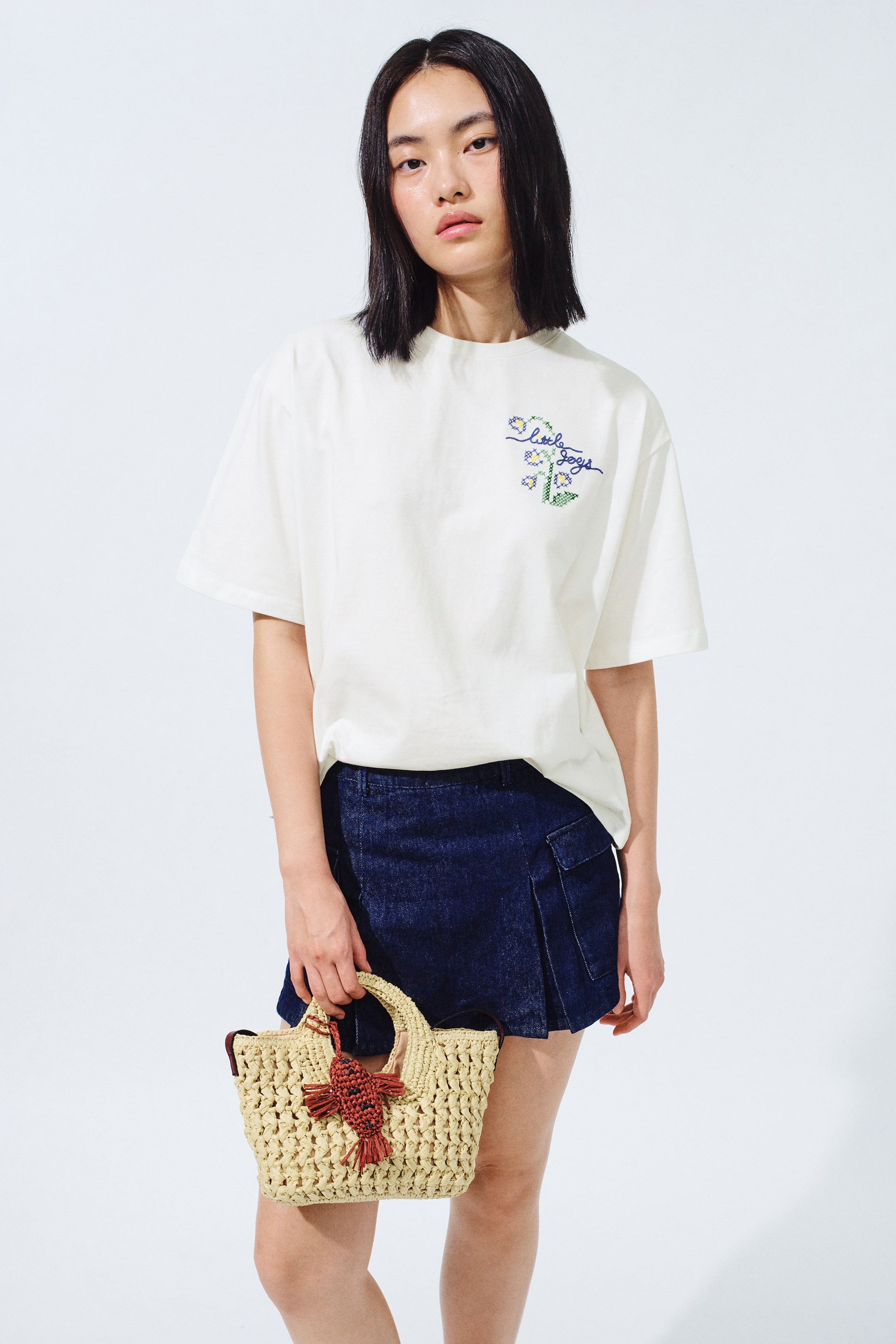 View larger image: The model is wearing an off-white embellished T-shirt crafted from cotton jersey. It showcases a ribbed crew neck, dropped shoulders, a relaxed fit with a straight-cut hem, and cross-stitch style floral embroidery alongside 'little joys' text on the left chest.