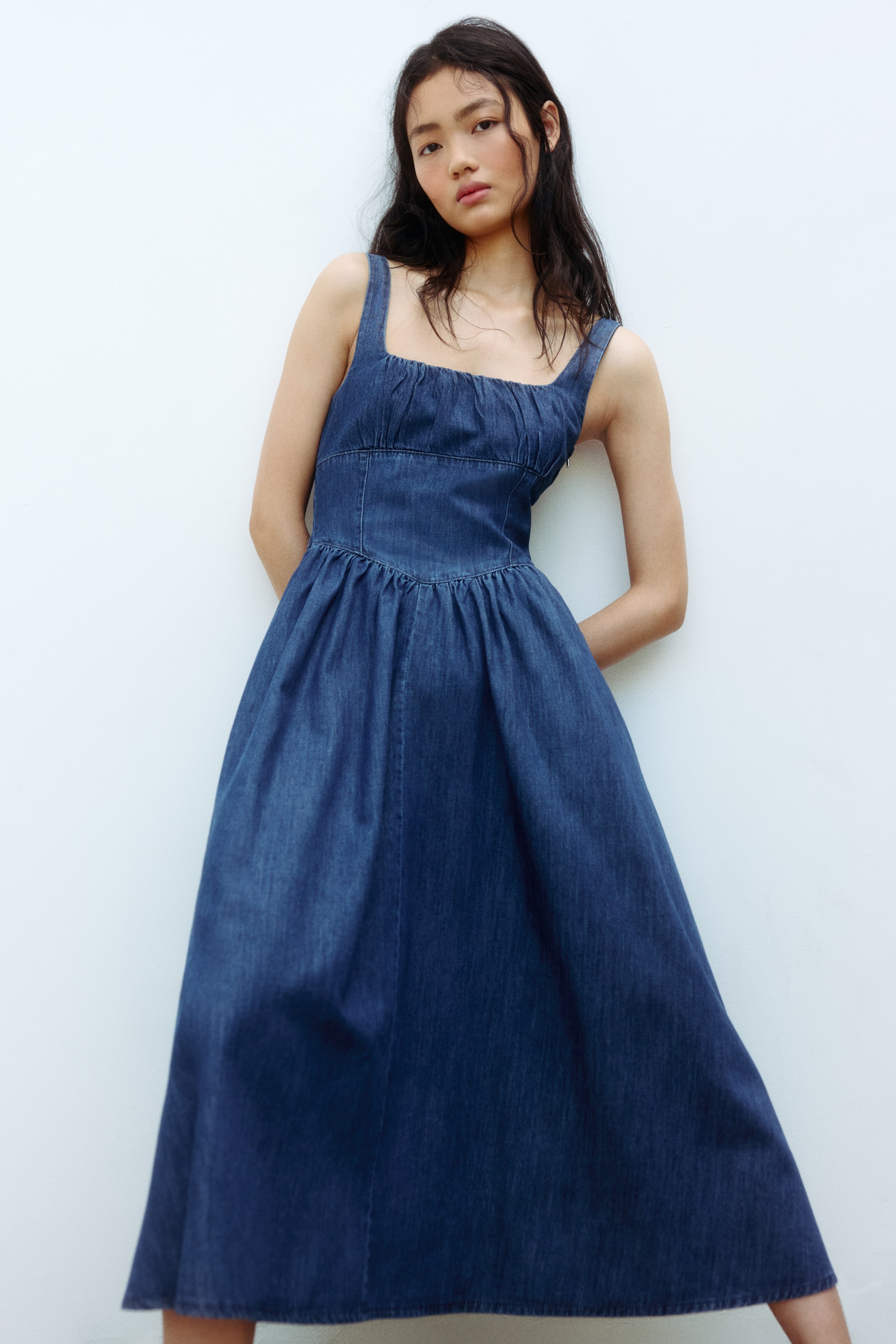 Voir une image plus grande: Robe midi en denim avec un décolleté carré et de larges bretelles. Le buste est froncé, et la taille ajustée se transforme en une jupe évasée pleine et froncée.