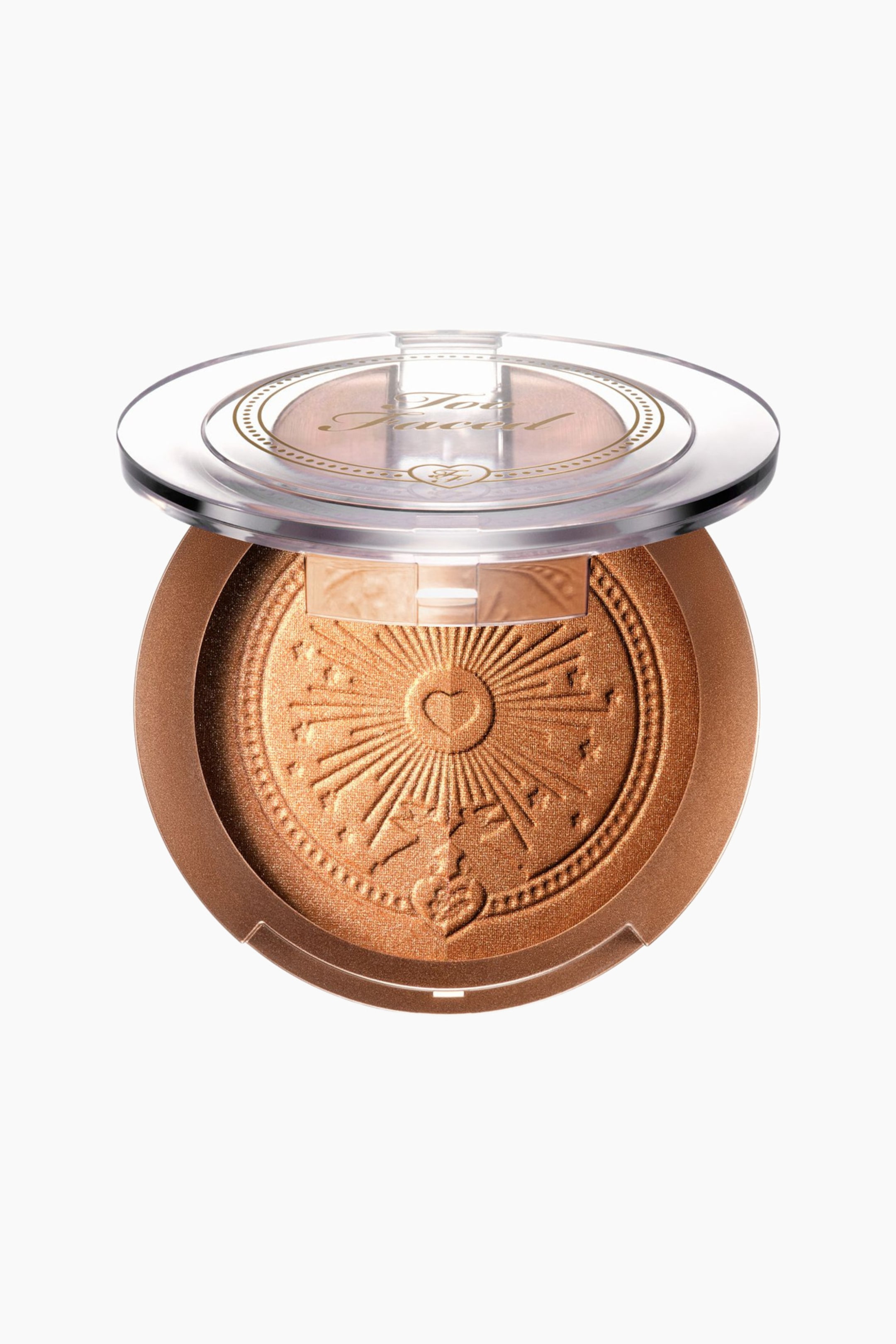 Vis større bilde: Et rundt, gyllen-bronse sminkepudder er vendt fremover, med et klart lokk som åpner seg oppover og viser "Too Faced" med en hjerte-logo i gull. Produktet inni er preget med et solstrålemønster, med et sentralt hjerte, en prikket kant, og mindre hjerte- og stjernemotiver.