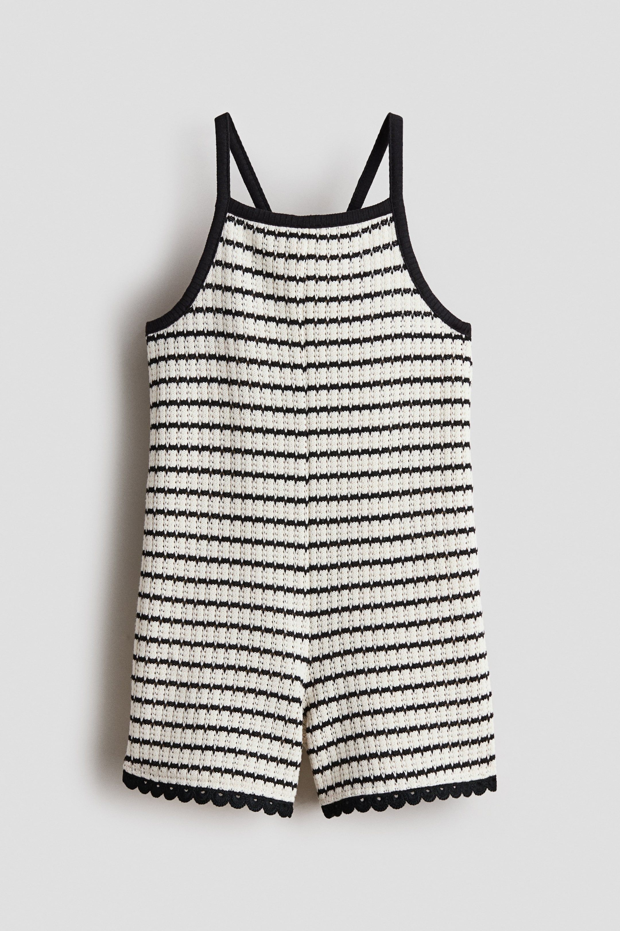 Ver imagen más grande: Vista FRONTAL de un mono de punto a rayas horizontales en negro y blanco roto, que muestra tirantes finos en negro y un ribete negro a lo largo del escote cuadrado y las sisas. Las perneras cortas terminan con un dobladillo negro festoneado.