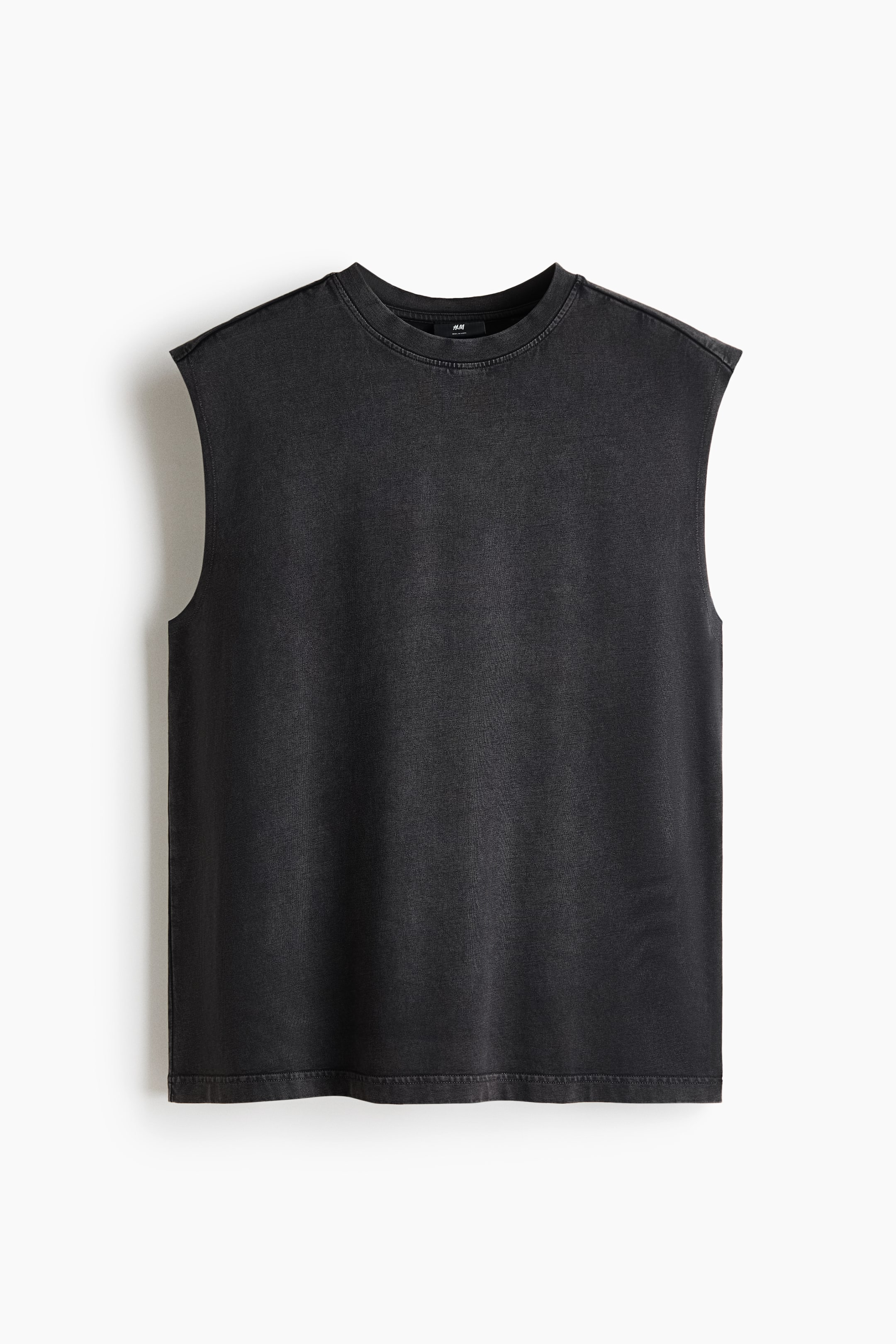 View larger image: A dark grey sleeveless t-shirt is lying flat, showcasing a washed finish, a ribbed crew neck, and extended shoulder seams with raw-cut armholes.