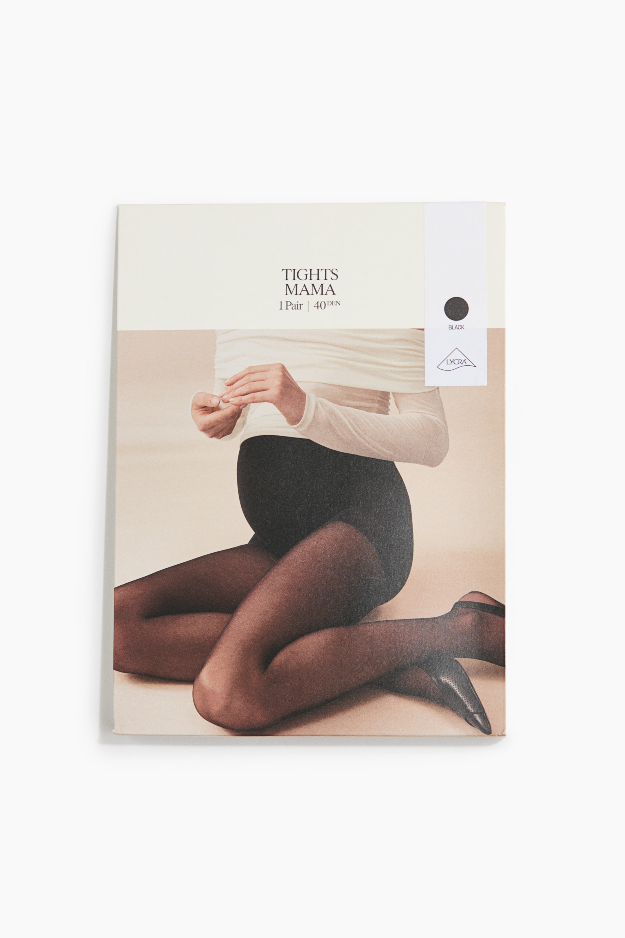 View larger image: The "Tights Mama" product packaging is standing upright, featuring a cream-coloured top panel with brand text, denier information, and a black colour swatch. A photographic image covers the lower panel, showing a pregnant person kneeling and wearing black sheer tights that cover the belly and legs.