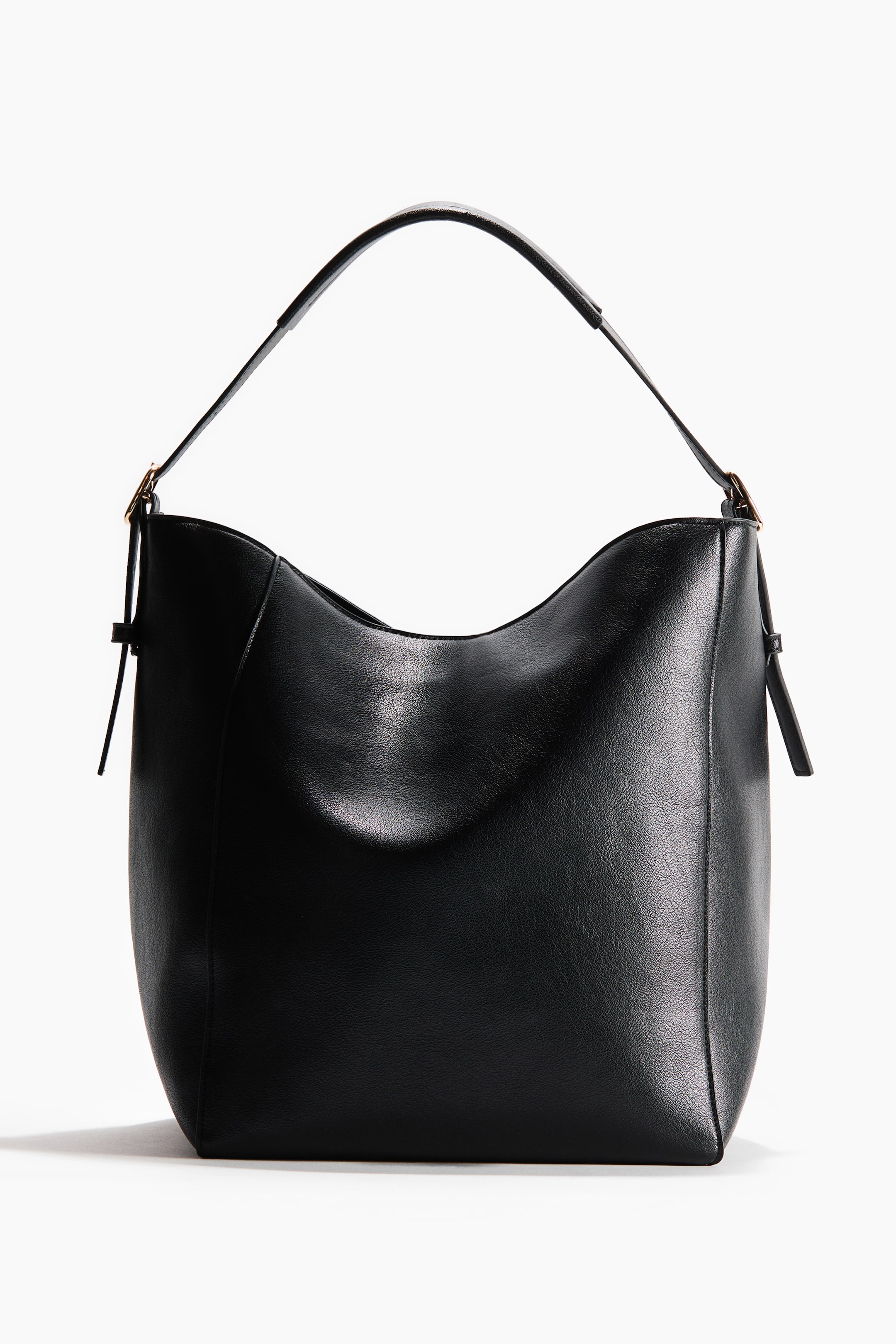 Visualizza immagine più grande: Una borsa shopper nera si presenta frontalmente, caratterizzata da una silhouette morbida e curva. Una singola tracolla è attaccata alla borsa con una fibbia dorata su ciascun lato.
