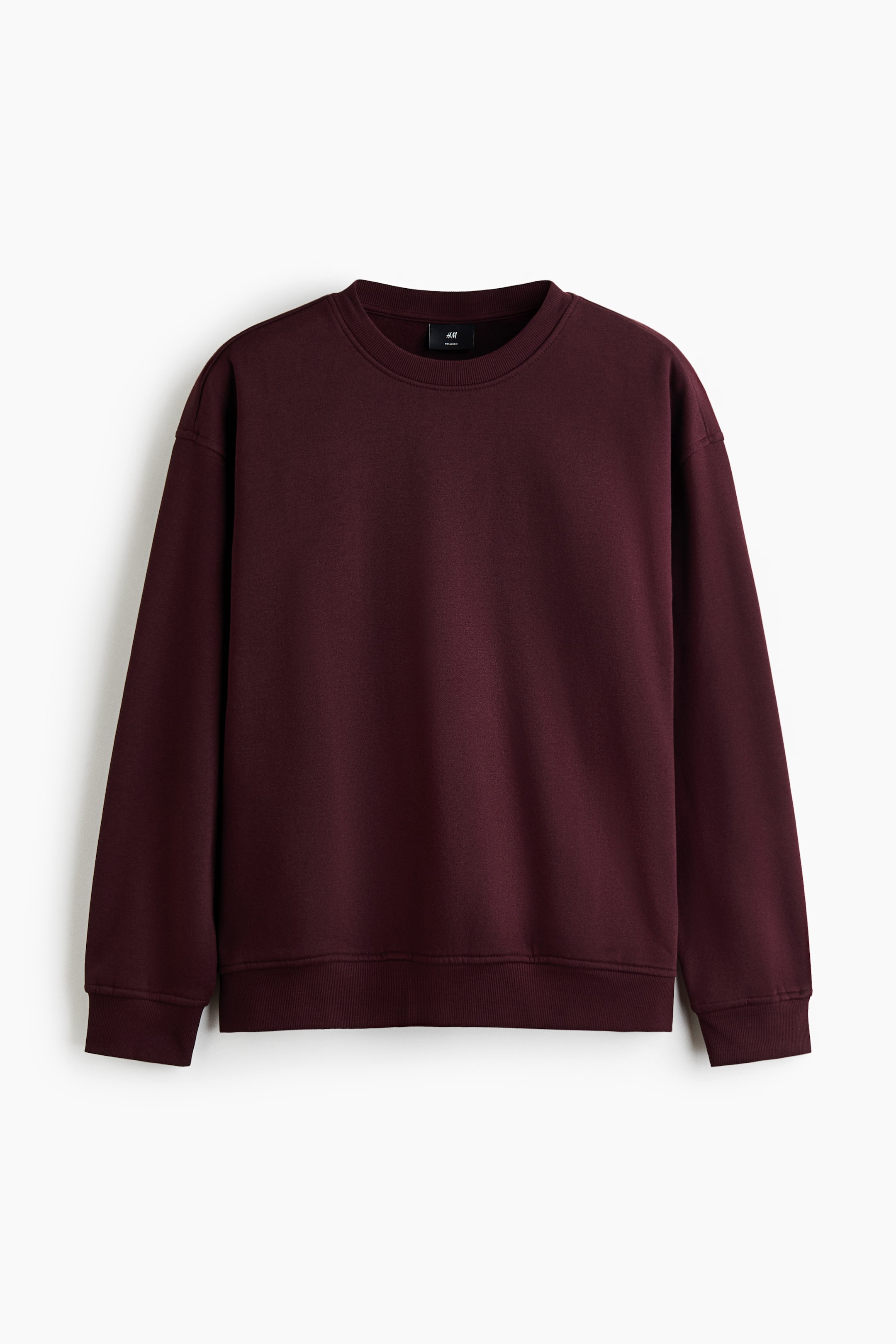 View larger image: A dark burgundy crew-neck sweatshirt is shown in a front-facing view, displaying a relaxed fit with dropped shoulders and long sleeves. The sweatshirt features a ribbed neckline, wide ribbed cuffs, and a matching ribbed hem.