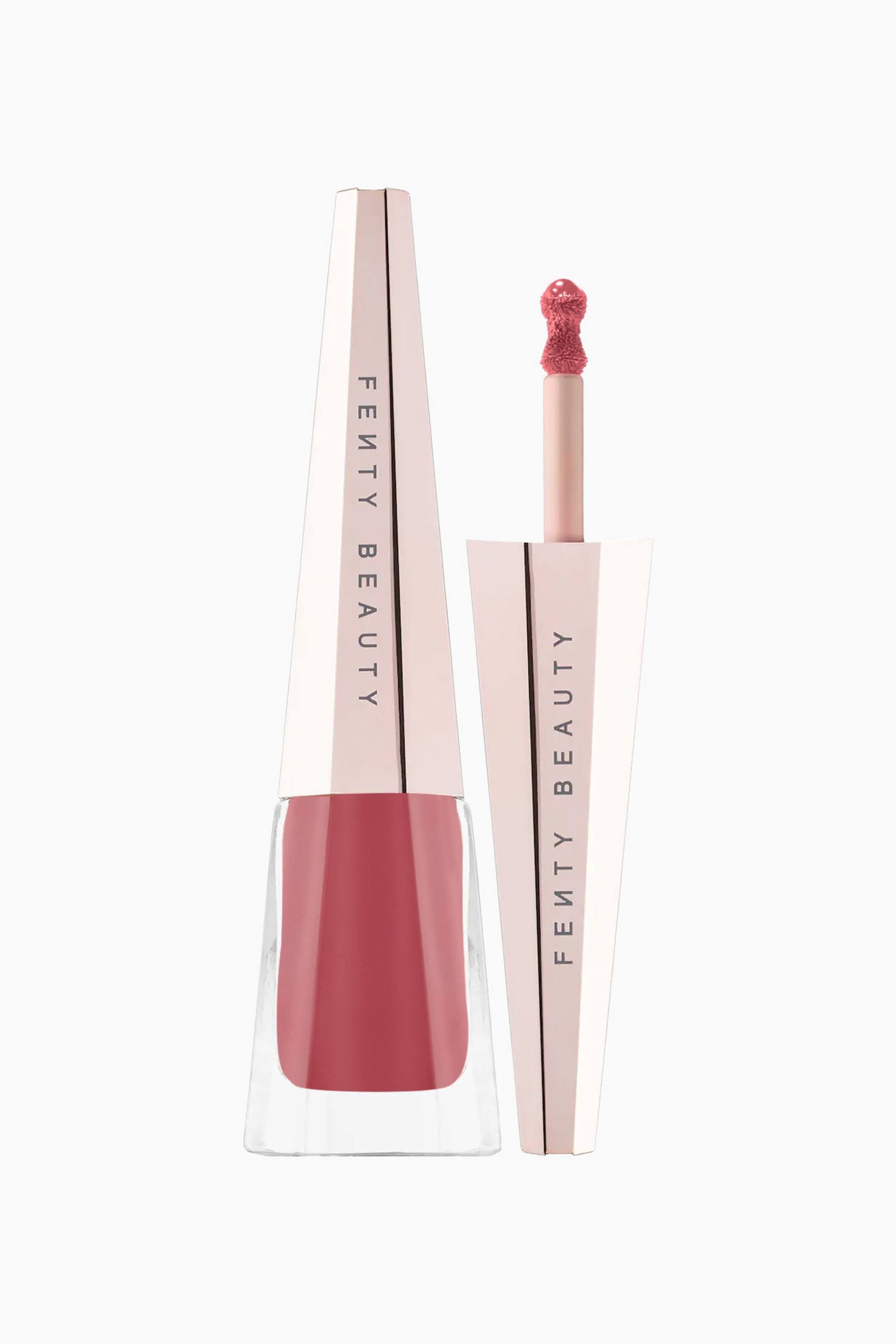 Näytä suurempi kuva: Stunna Lip Paint Longwear Fluid Lip Color seisoo pystyssä esitellen levenevää, kirkasta lasipulloa, joka on täytetty pölyisen ruusun sävyisellä nestemäisellä huulipunalla ja viimeistelty korkealla, fasettipintaisella ruusukultaisella korkilla. Pullon vieressä kierretön applikaattoripuikko seisoo pystysuorassa ja näyttää tarkkuussienen kärjellä varustetun applikaattorinsa, joka on päällystetty samalla ruusuisella sävyllä.