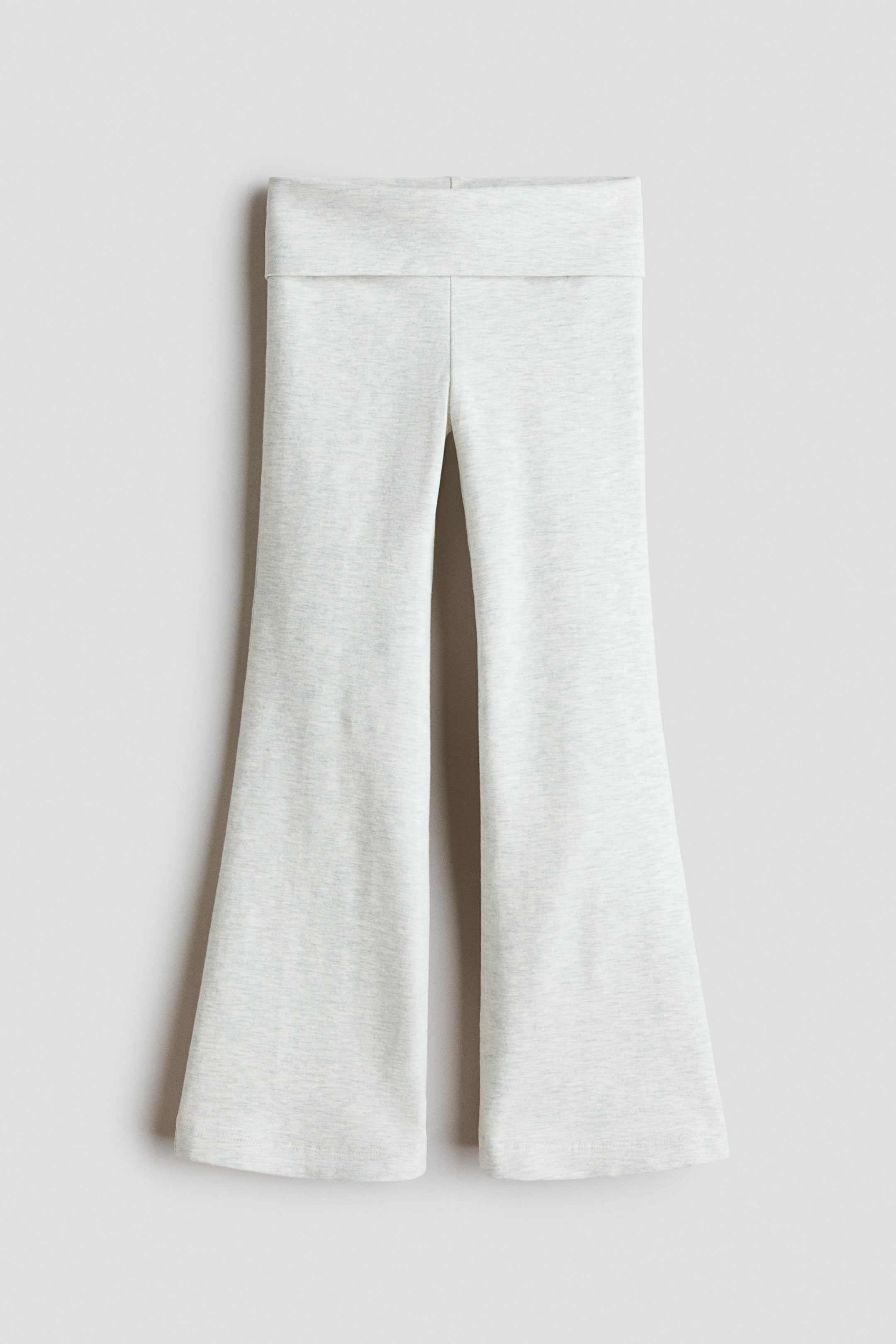 View larger image: A pair of light grey knit pants is hanging facing the front, featuring a wide fold-over waistband and legs that flare out toward the hem.