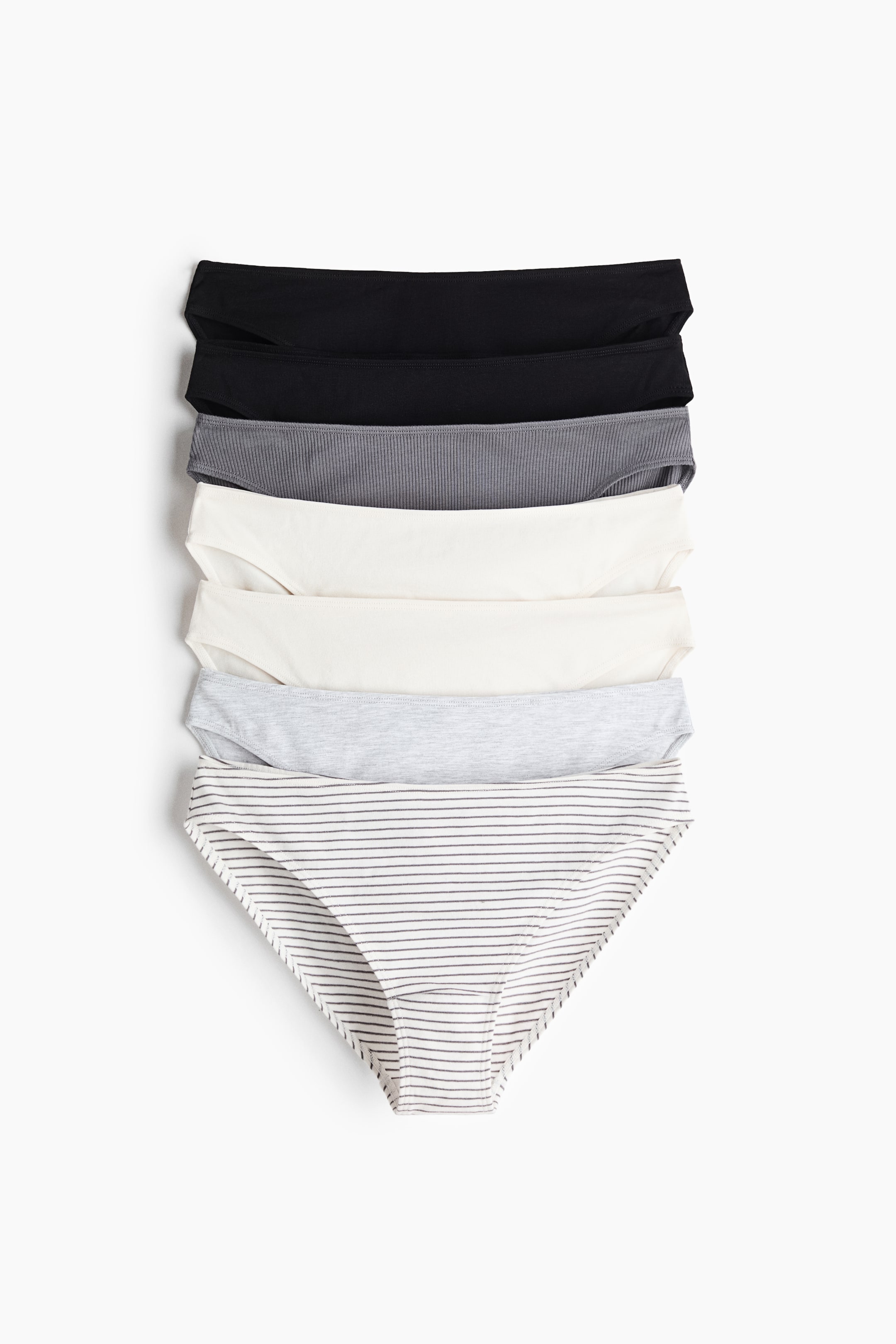 View larger image: Six pairs of cotton jersey briefs are stacked vertically, showing their front view. The stack includes two black pairs, one grey ribbed pair, two cream pairs, and one light grey pair with thin horizontal stripes. All briefs feature a mid-rise waist.