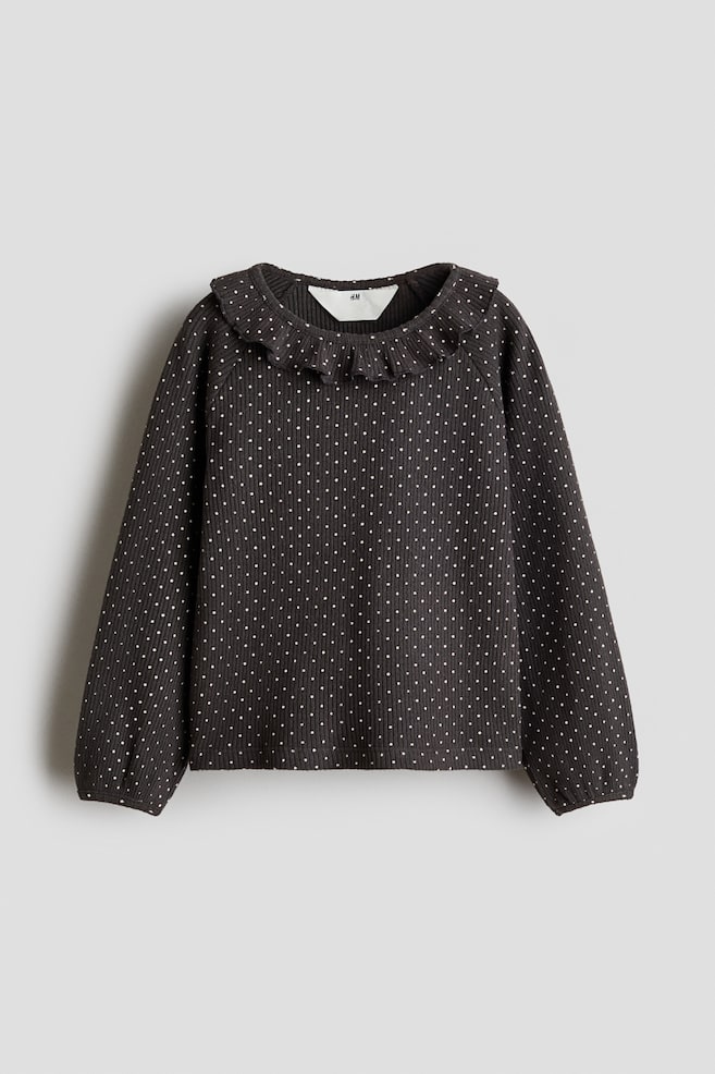 Dieses dunkelgraue Jersey-Top aus gerippter Baumwolle mit weiÃem Punktmuster ist frontal ausgerichtet und verfÃ¼gt Ã¼ber einen runden Kragen mit RÃ¼schenbesatz sowie lange RaglanÃ¤rmel mit schmaler Einfassung an den BÃ¼ndchen. - 1