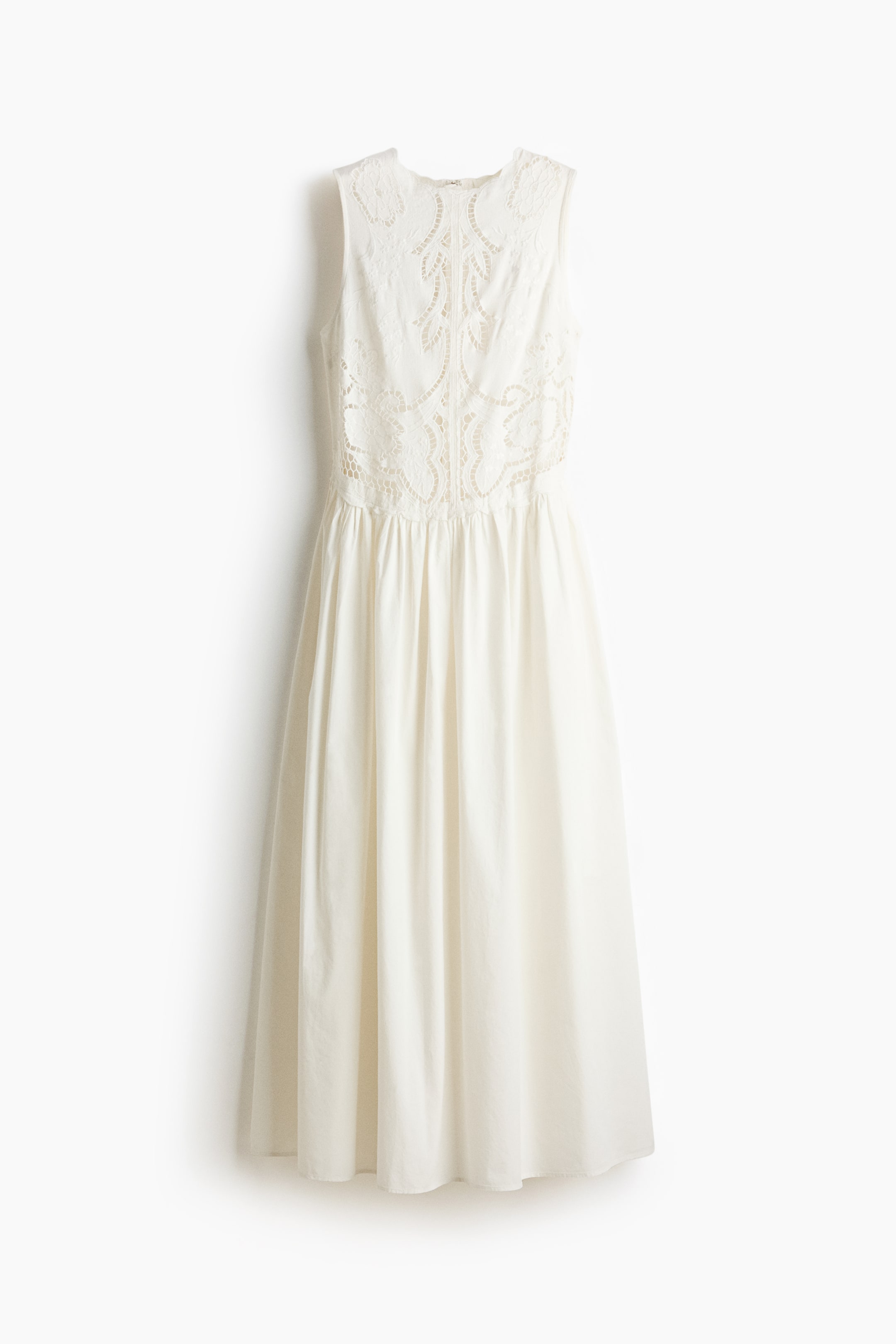 View larger image: The off-white dress showcases its front, featuring a sleeveless bodice adorned with intricate white floral-patterned lace embroidery that transitions into a gathered, flowing skirt.