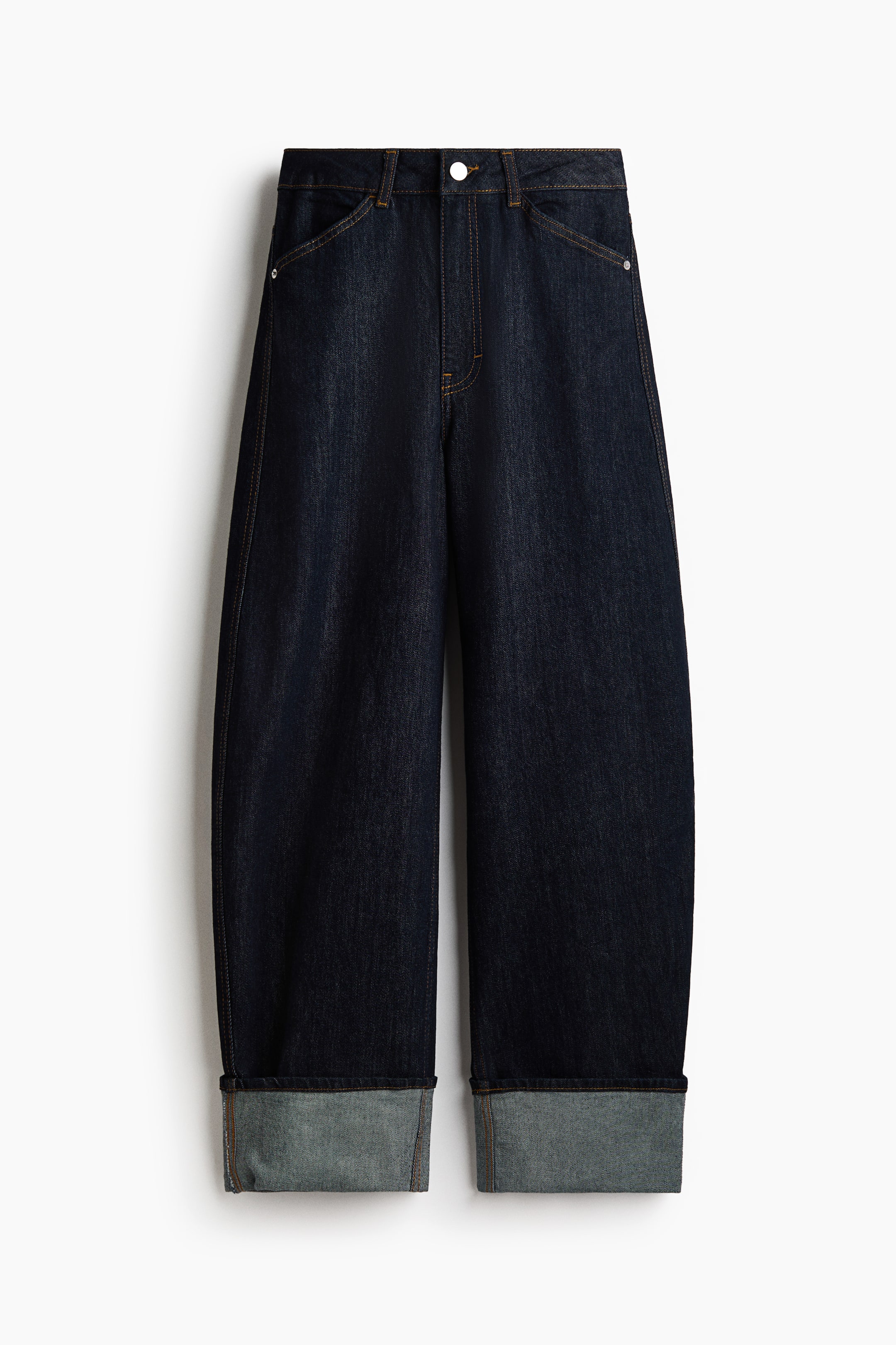 Büyük resmi görüntüle: Koyu indigo denim kot pantolon, önden gösterilmektedir; kemer halkaları bulunan normal bel, düğme kapama ve çapraz ön ceplere sahiptir. Kot pantolon, geniş, kıvrılmış paçalara doğru daralan kavisli ve hacimli bir paça formu sergilemektedir.