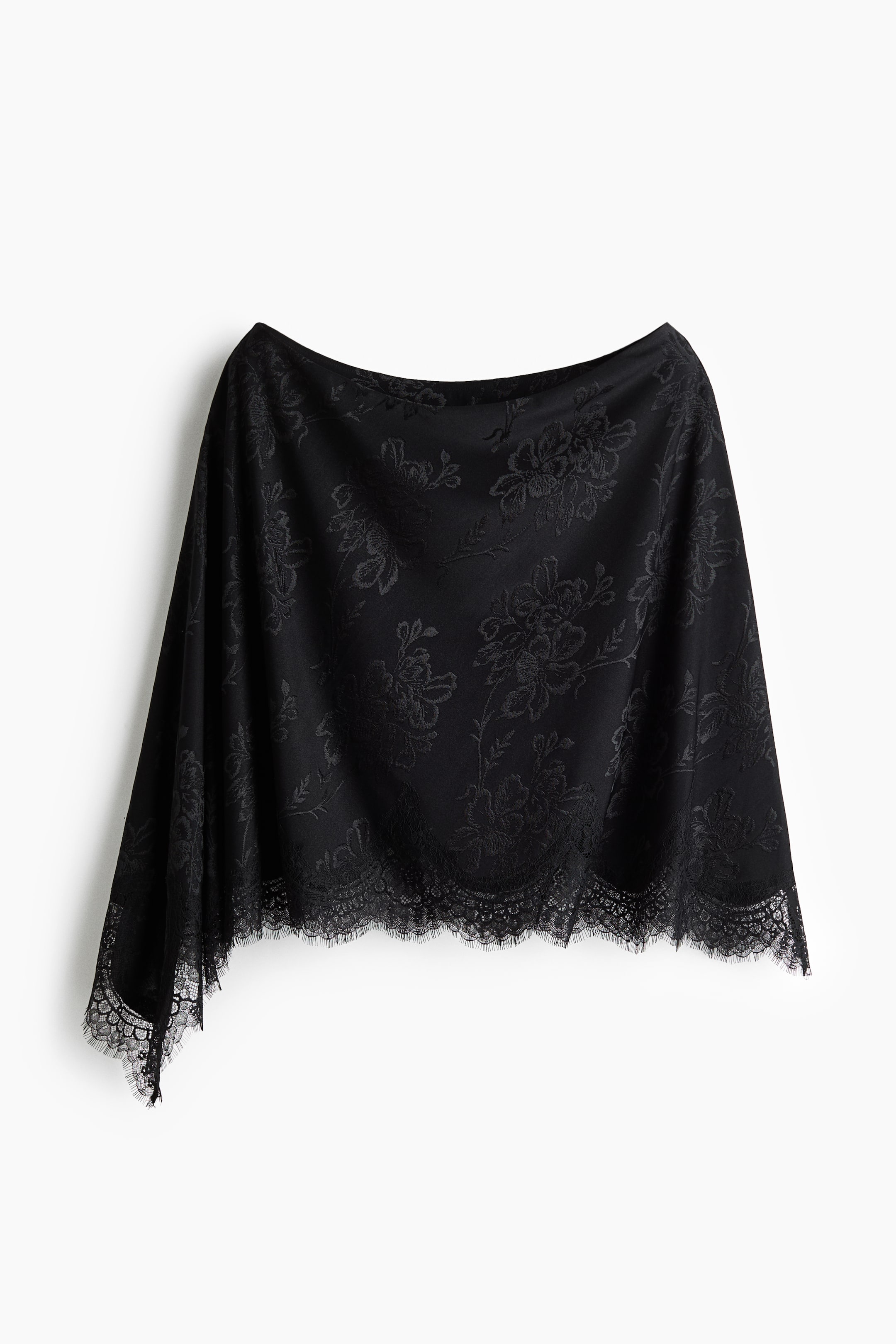 Grotere afbeelding bekijken: Een zwarte losvallende one-shoulder capetop hangt aan de voorkant en benadrukt het gedrapeerde silhouet en de asymmetrische halslijn. De stretch jacquard jersey-stof toont een ton-sur-ton bloemenpatroon en eindigt in een asymmetrische zoom, afgewerkt met verfijnde geschulpte kanten bies.