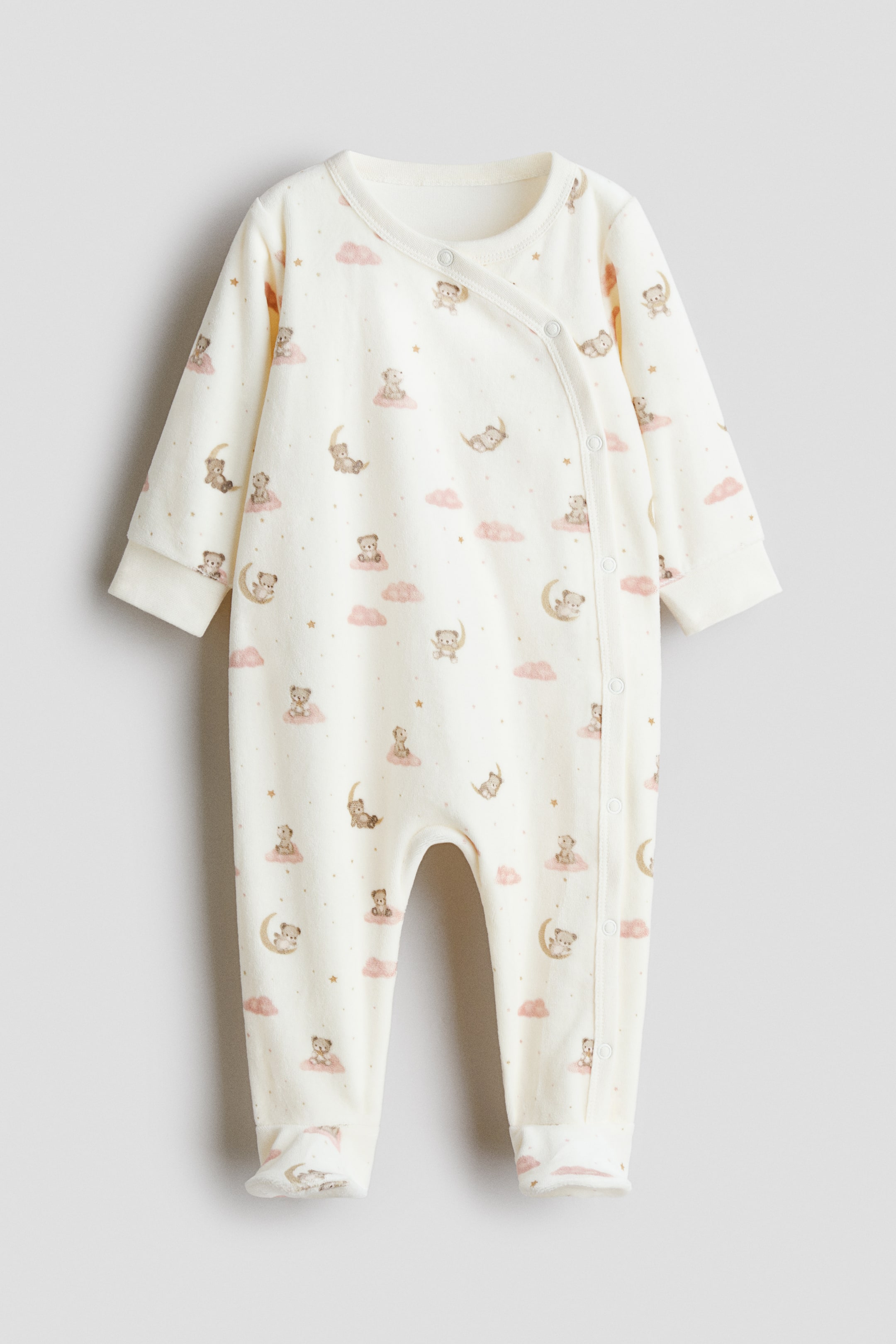 View larger image: This front-facing, off-white baby sleepsuit features an all-over print of small teddy bears, pink clouds, and stars. It has long sleeves with ribbed cuffs, integrated feet, and an asymmetrical snap-button closure running from the crew neck down the left side.