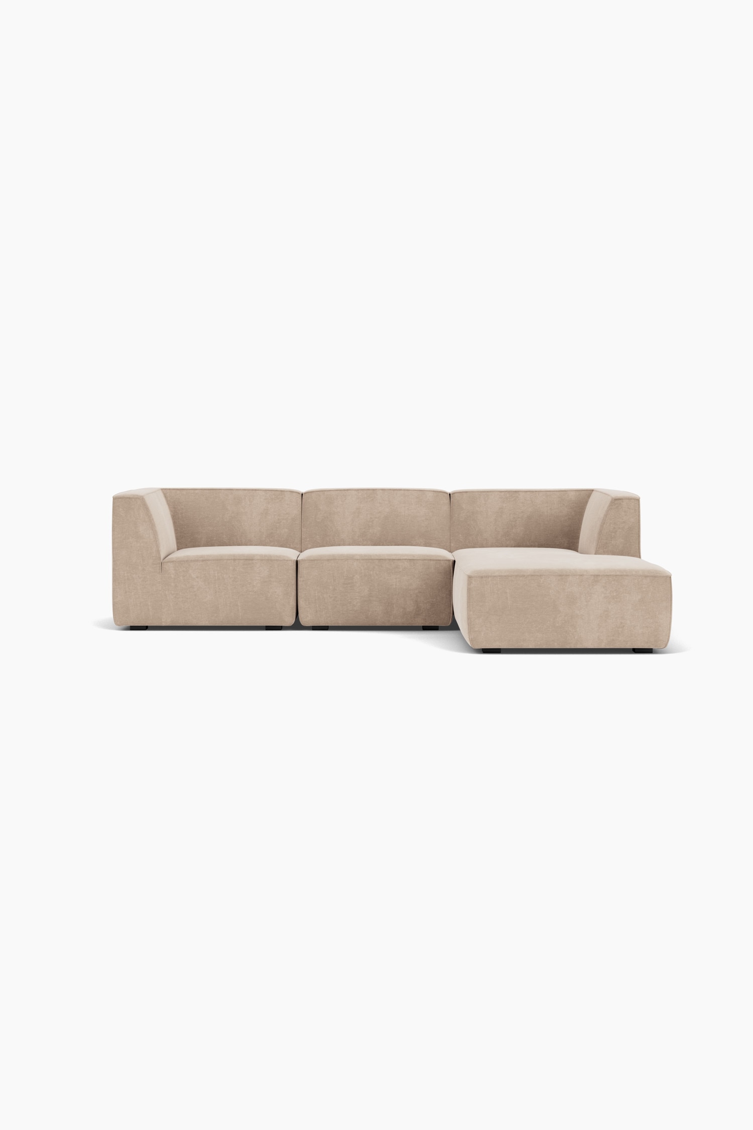 Un canapÃ© sectionnel modulaire en tissu beige sâÃ©tend en une longue mÃ©ridienne orientÃ©e vers lâavant-plan. Le canapÃ© bas prÃ©sente des coussins aux lignes Ã©purÃ©es et aux formes cubiques, avec des coutures passepoilÃ©es et un coussin dÃ©coratif carrÃ© assorti, appuyÃ© contre son dossier inclinÃ©.